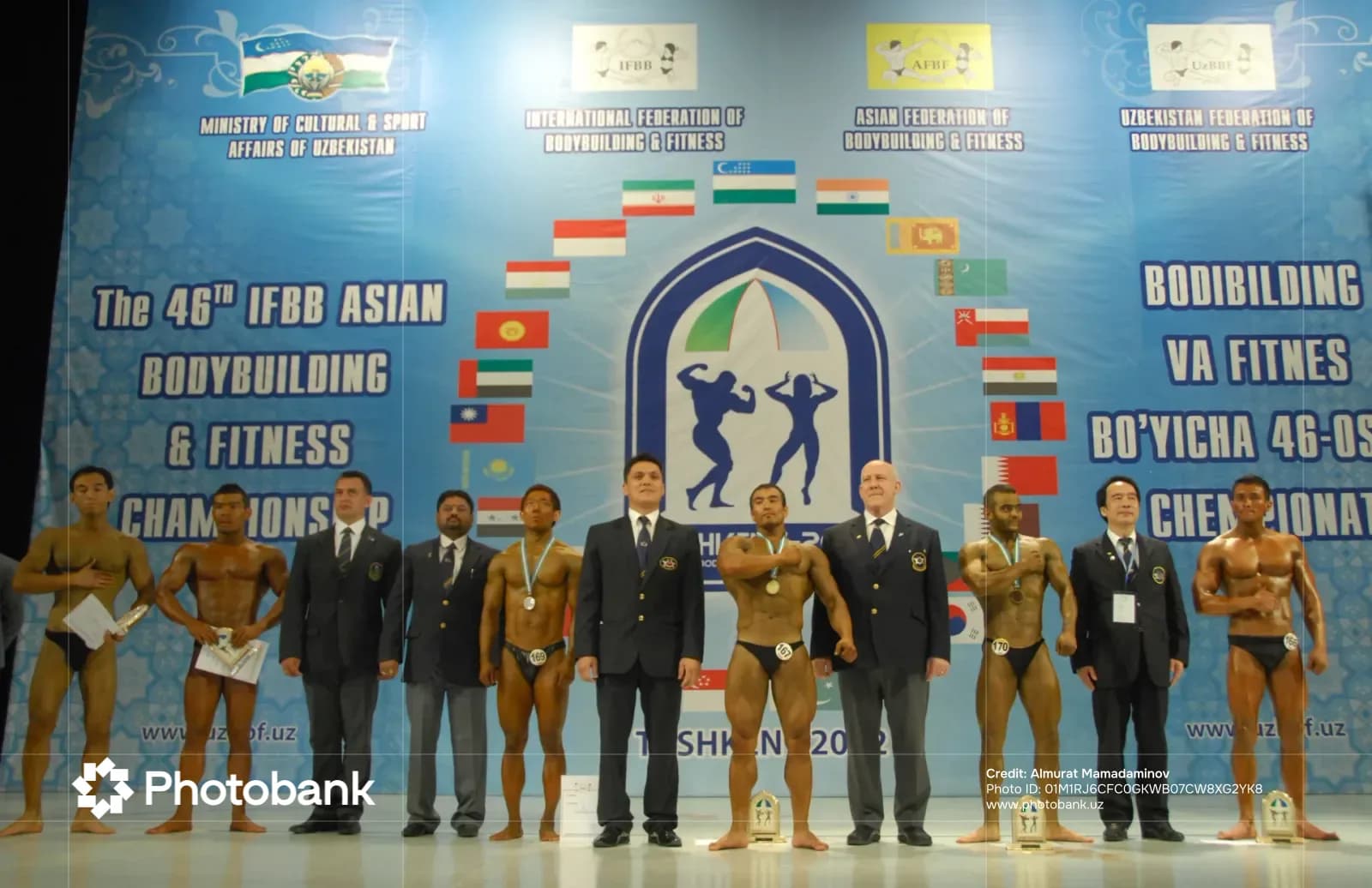 Athletes and officials stand on stage at a bodybuilding competition