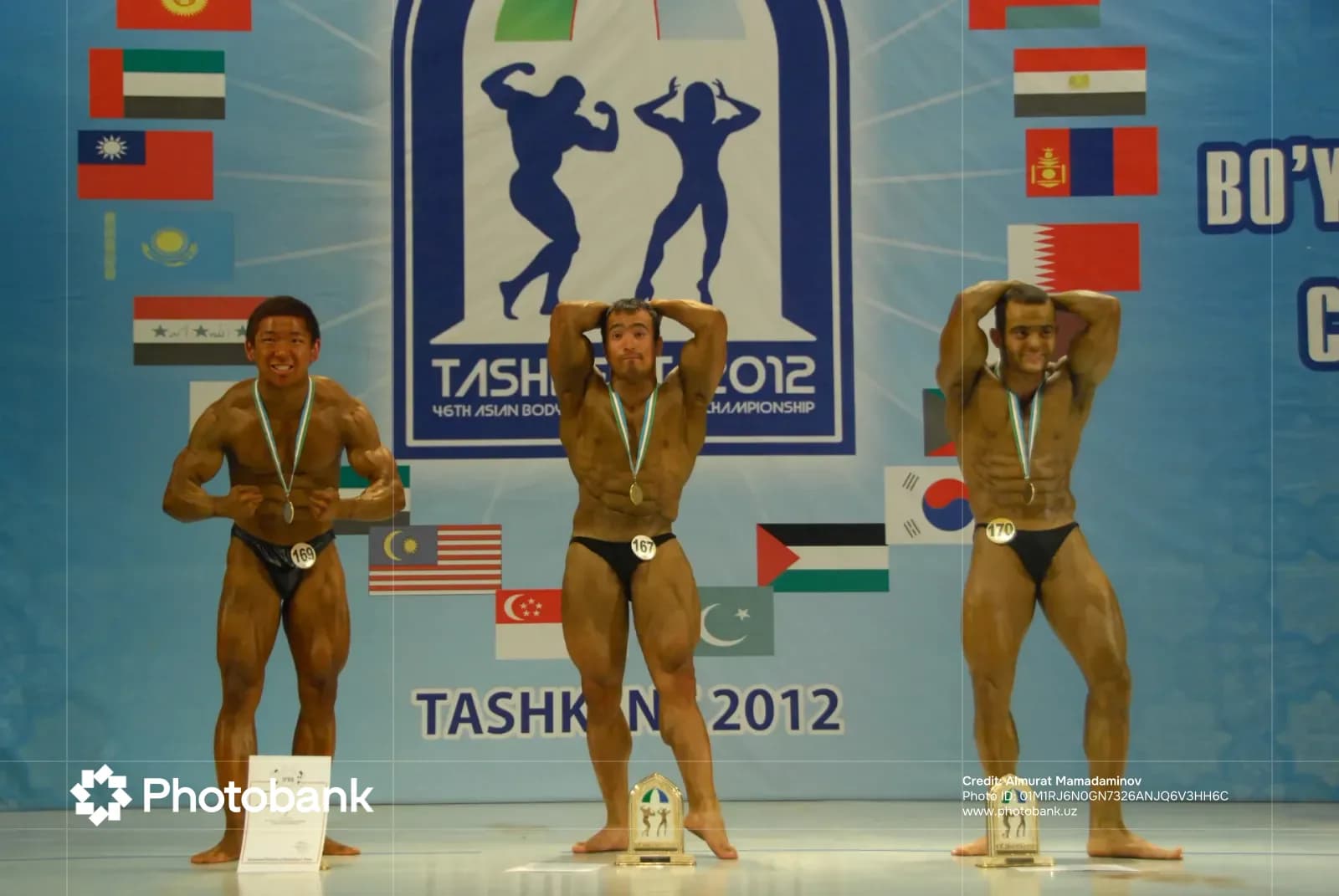 Bodybuilders posing with medals on stage
