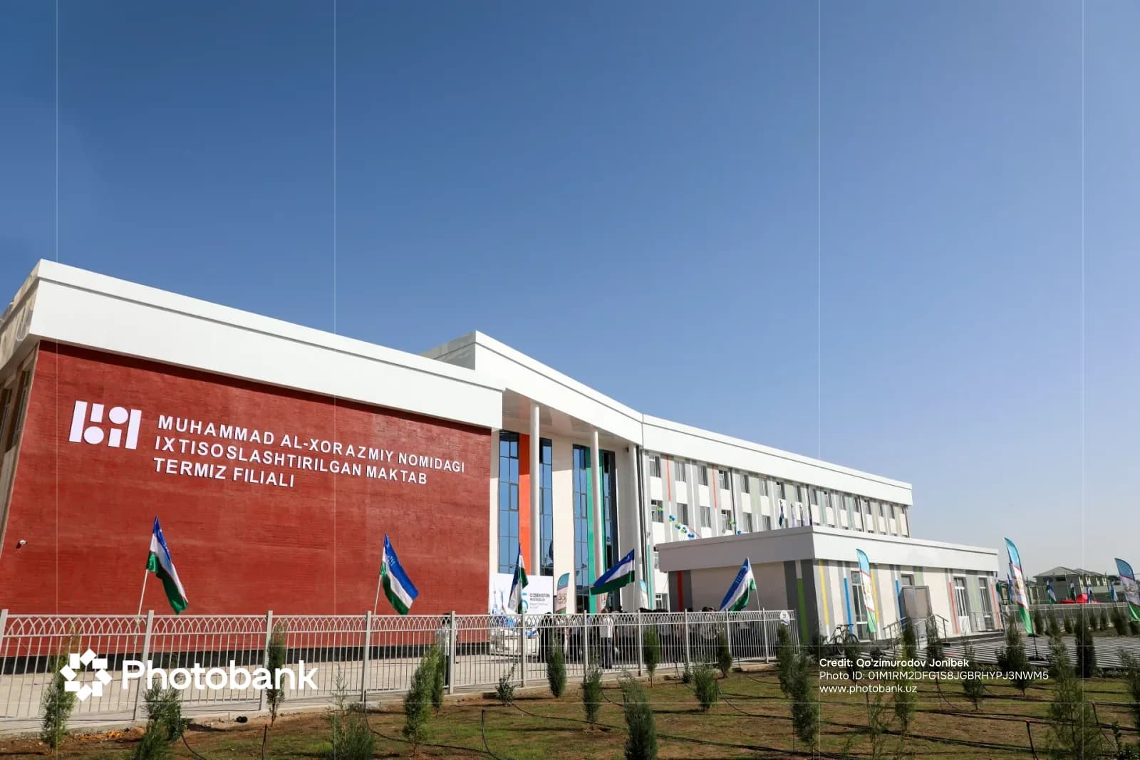 Exterior view of a modern school building with red and white facade under a clear blue sky
