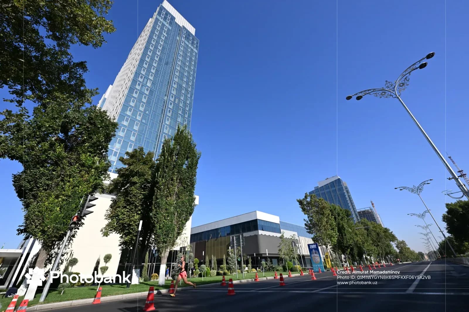 Person running along a city street lined with modern skyscrapers