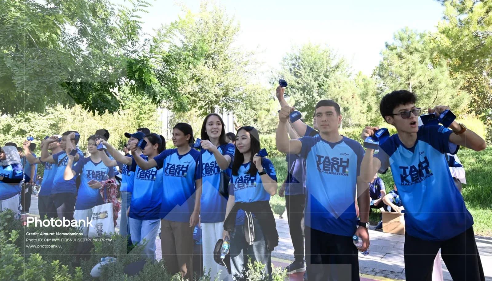 People in matching blue shirts holding items outdoors