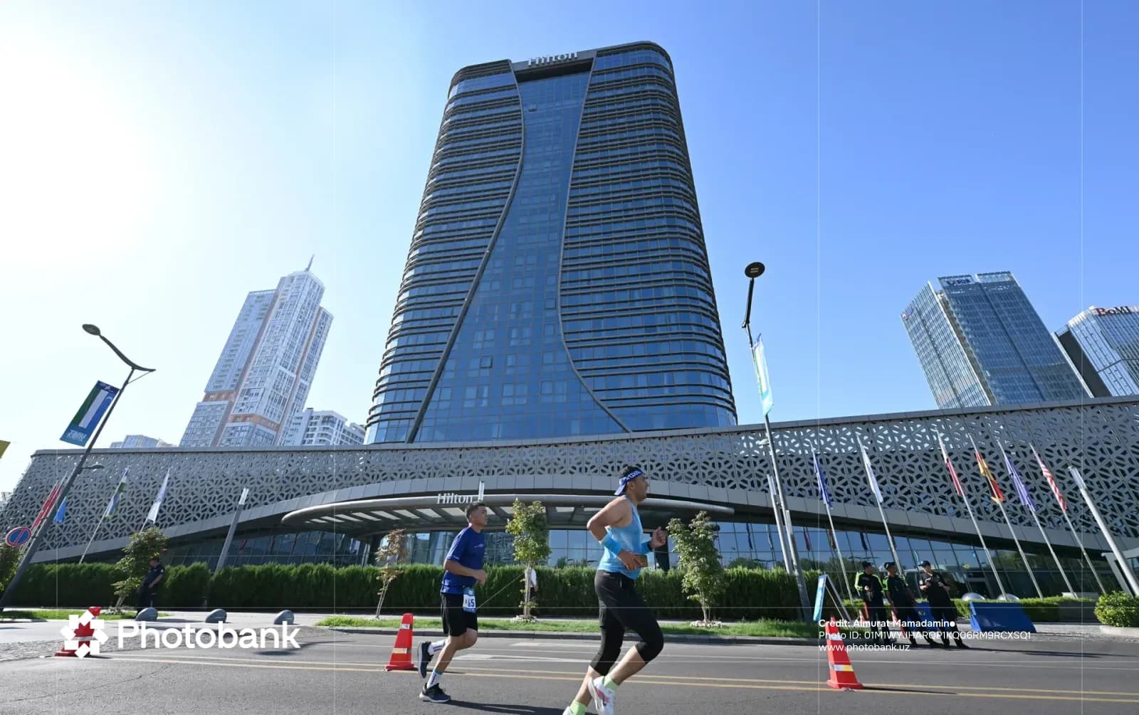 People running on a city street past a modern building
