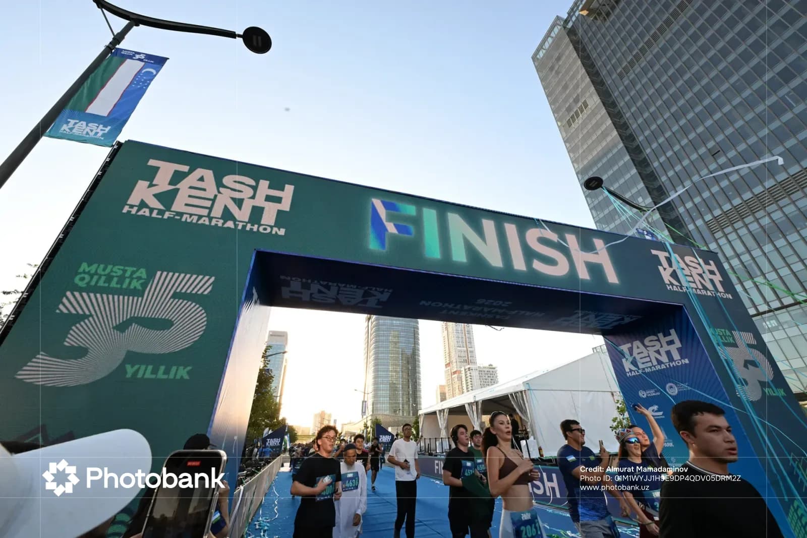 Runners cross the finish line under a large branded archway