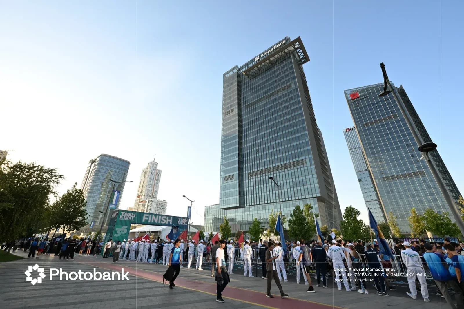 People gathered near modern high-rise buildings and finish line arch
