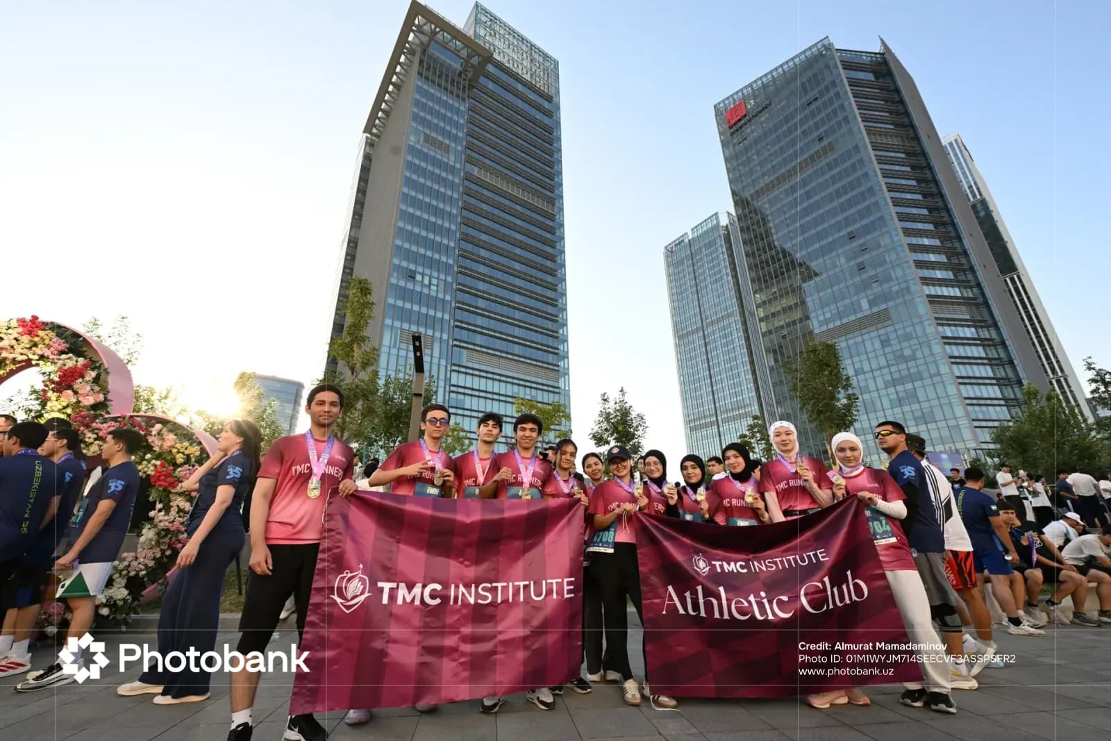 Group holding athletic club banner in front of modern buildings