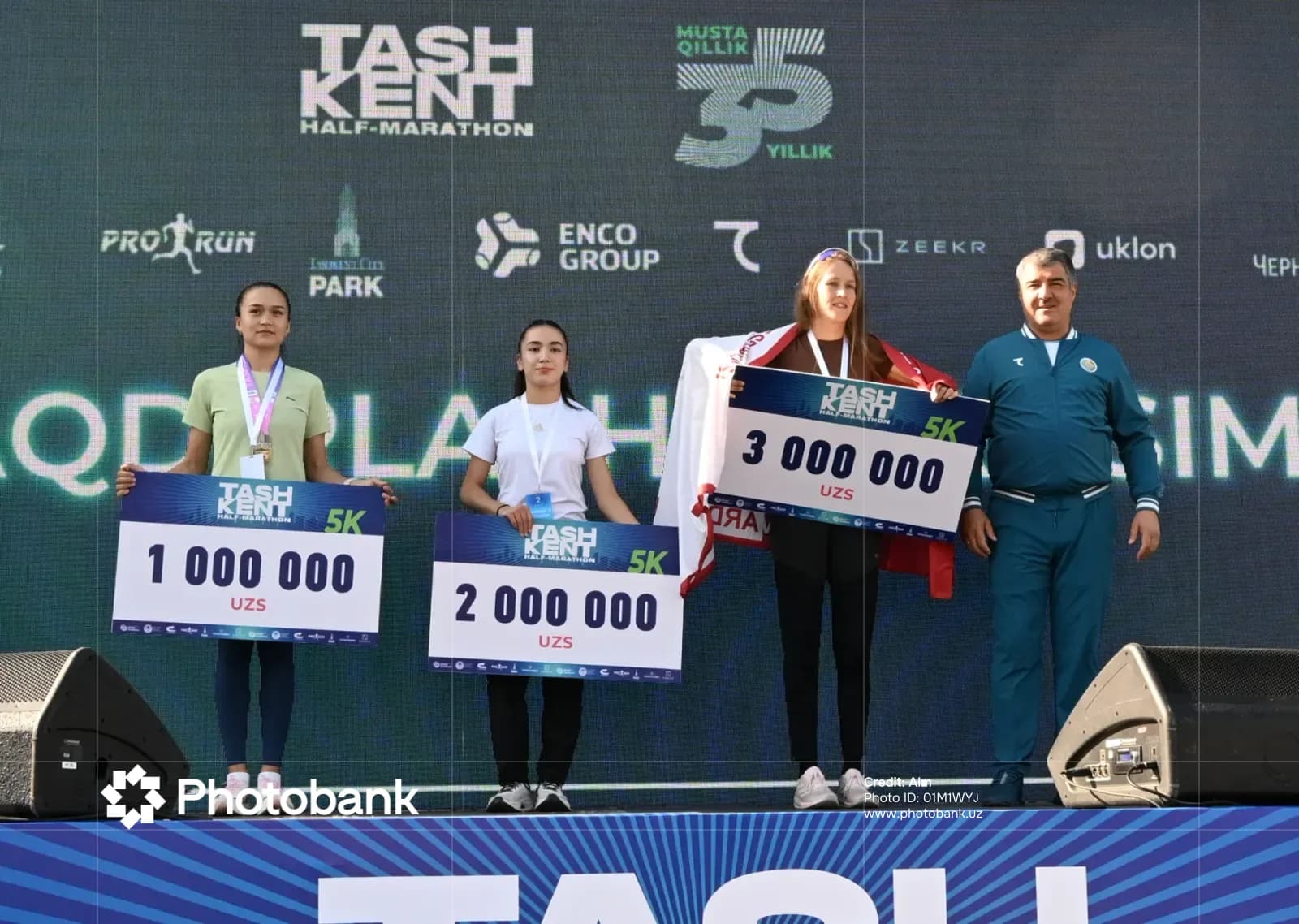 Athletes standing on podium holding prize checks