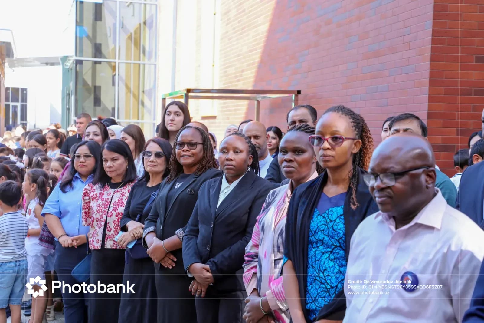 Diverse group of people standing outdoors near a brick building