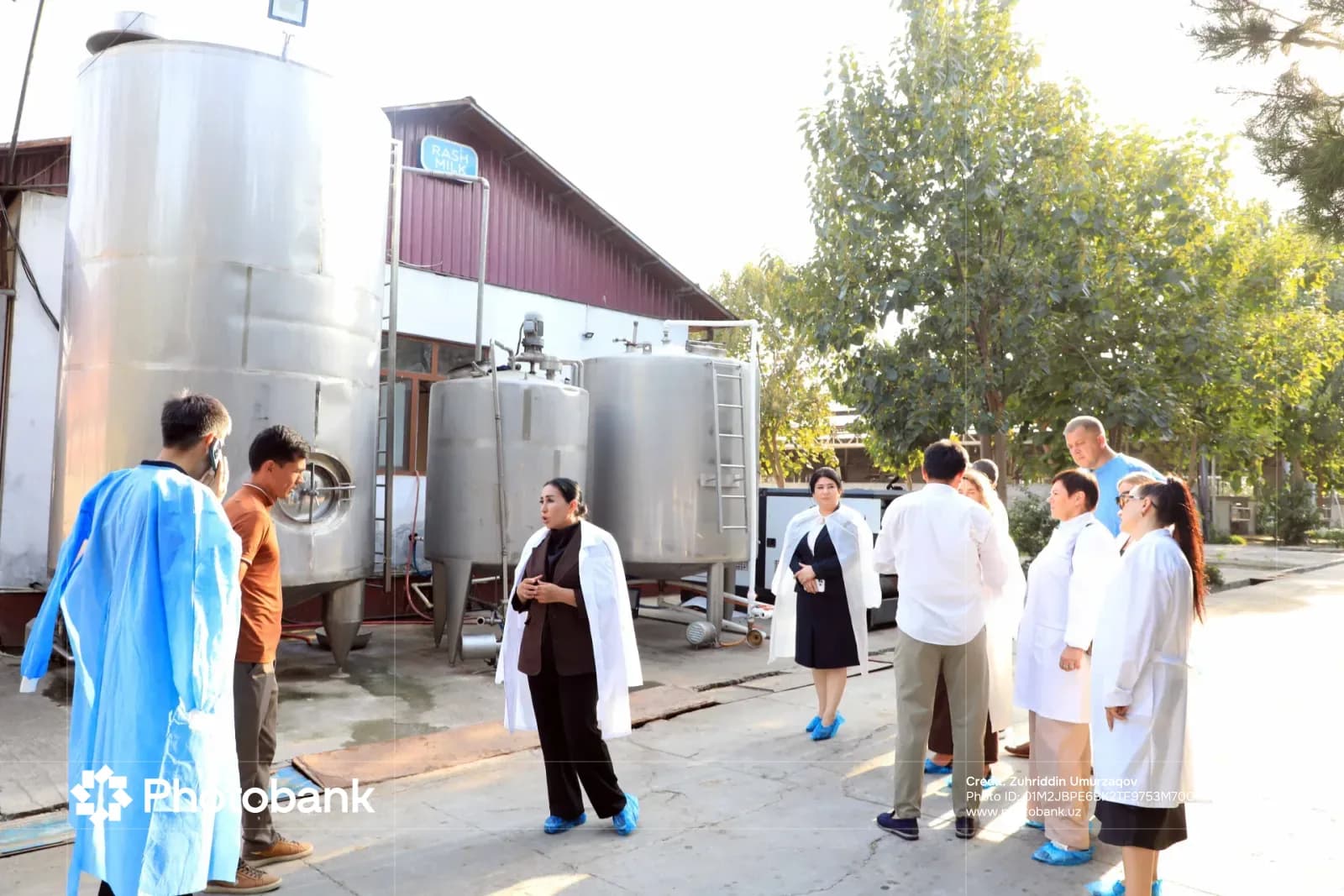 Люди собрались возле промышленных резервуаров на производственном объекте