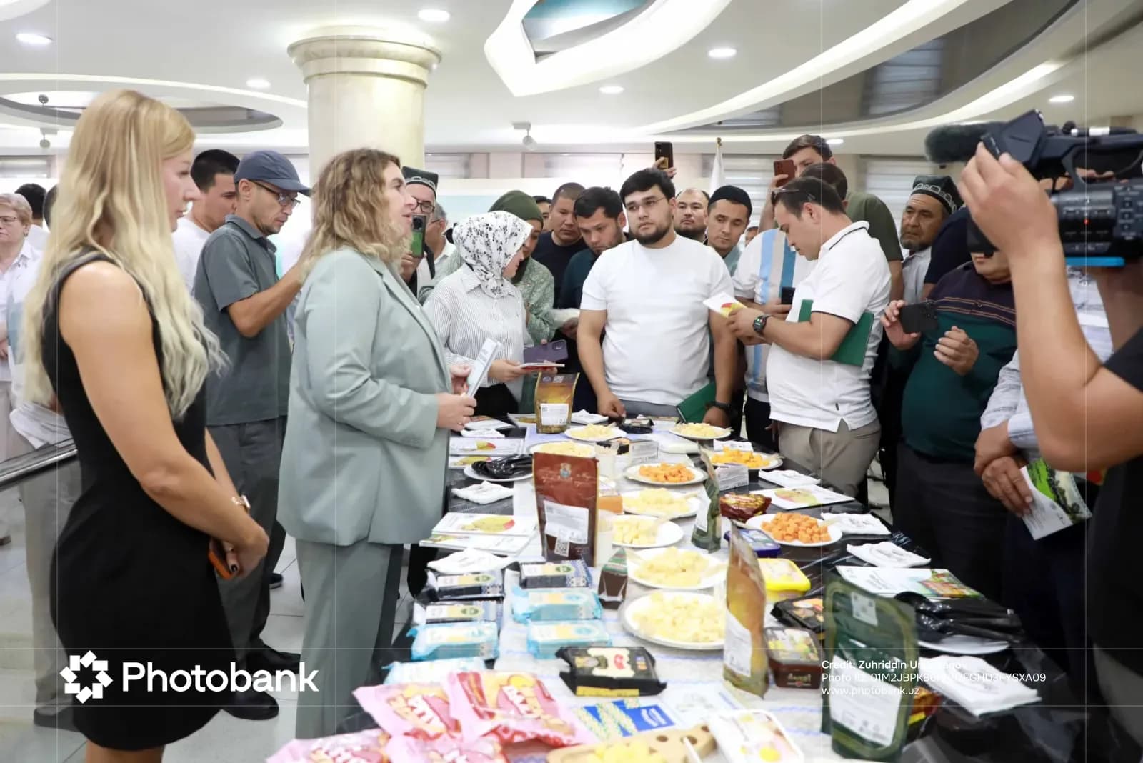 Люди собрались вокруг столов, выставляющих различные продукты питания в помещении.