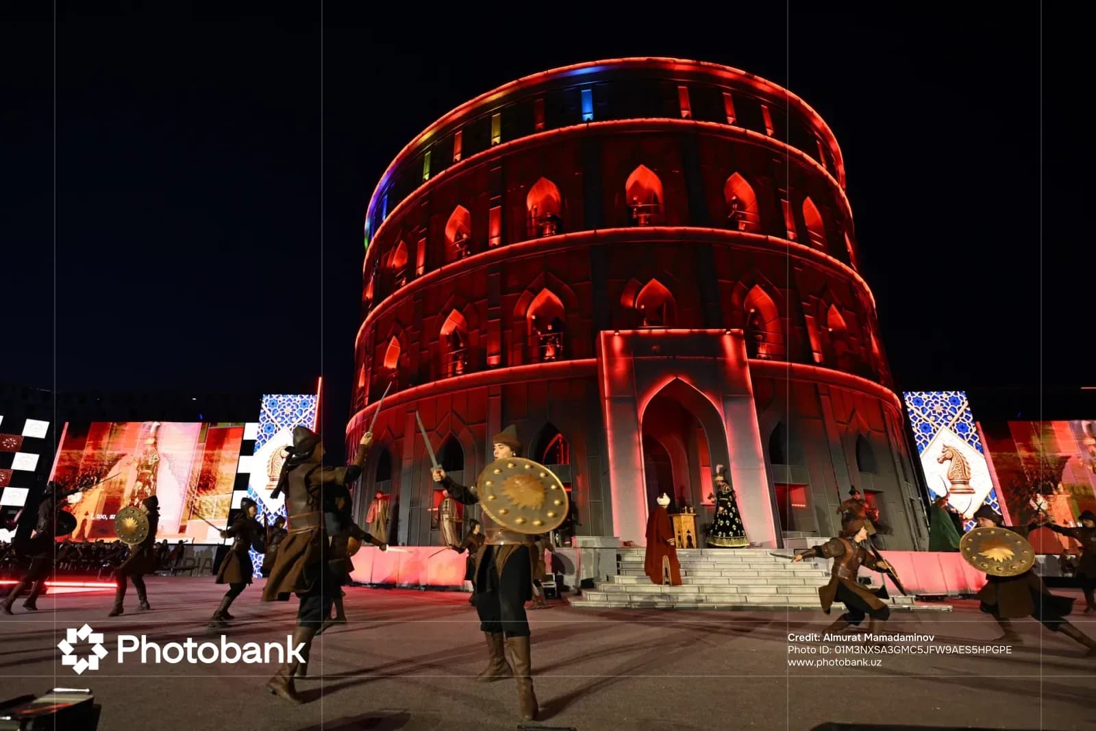 People performing with swords and shields in front of a illuminated building at night