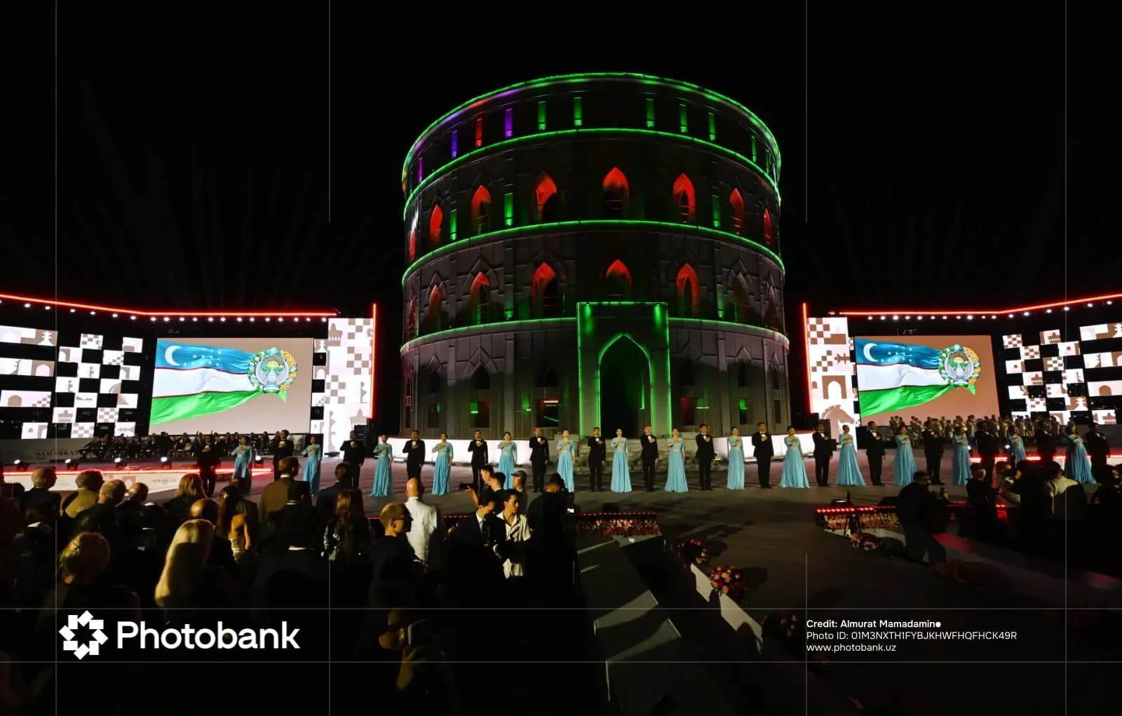 People gathered at an illuminated evening event with screens and circular architecture