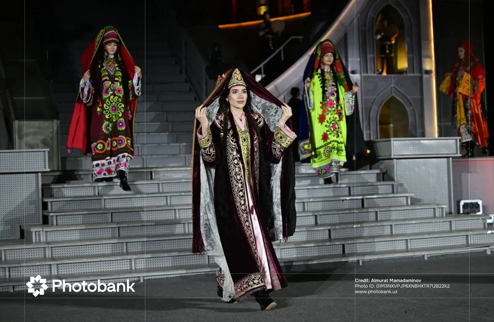 People presenting traditional clothing on a tiered stage