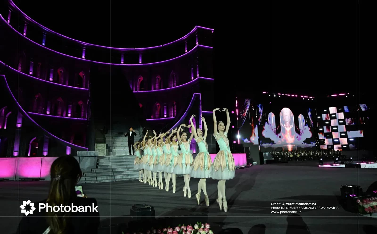 Performers in tutus dance on a stage at night