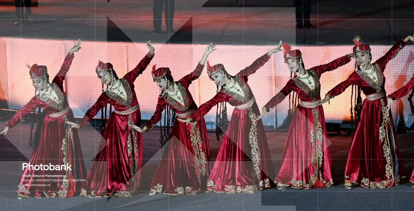 Dancers perform in traditional red dresses and headwear on stage
