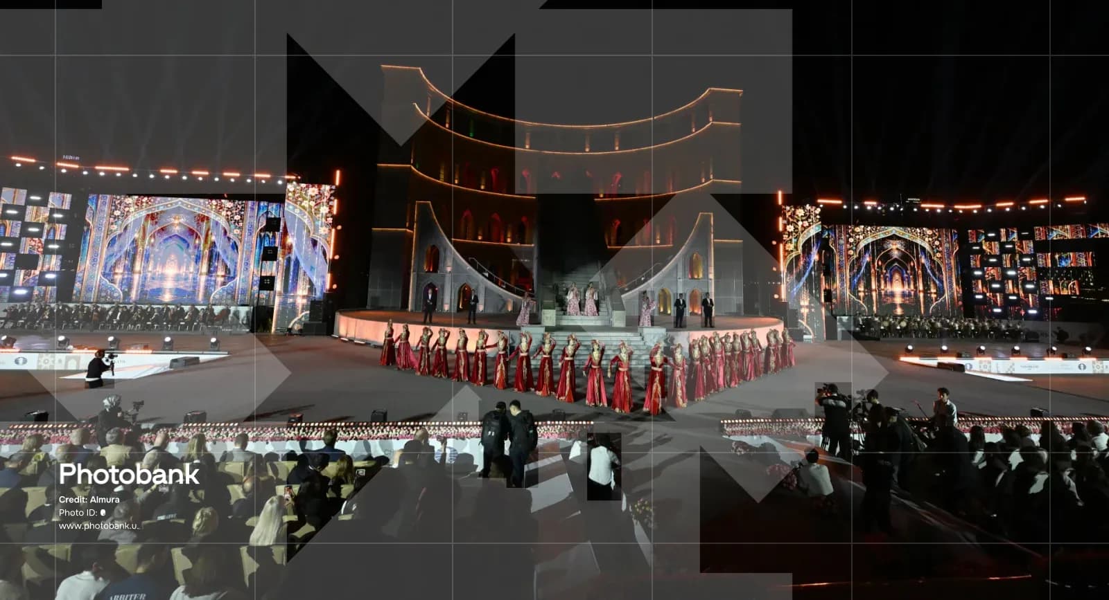 Performers in traditional red dresses on an outdoor stage at night