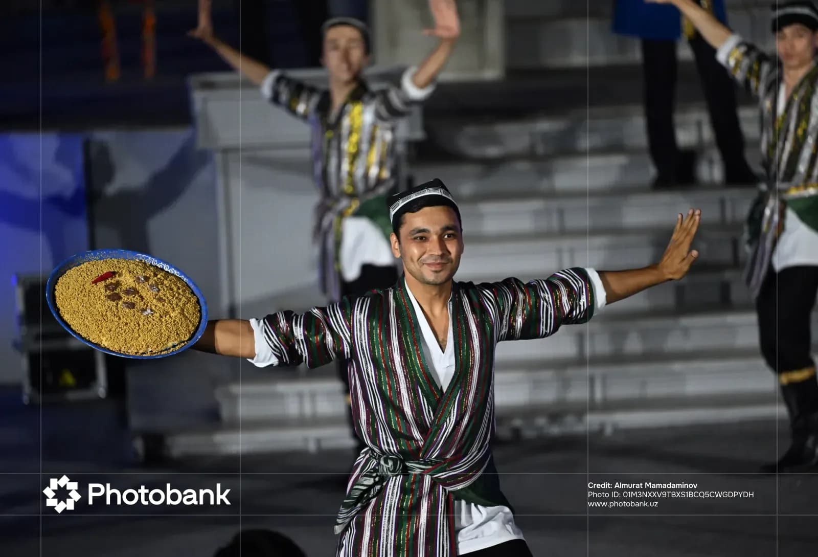 Performers in traditional clothing holding a large plate