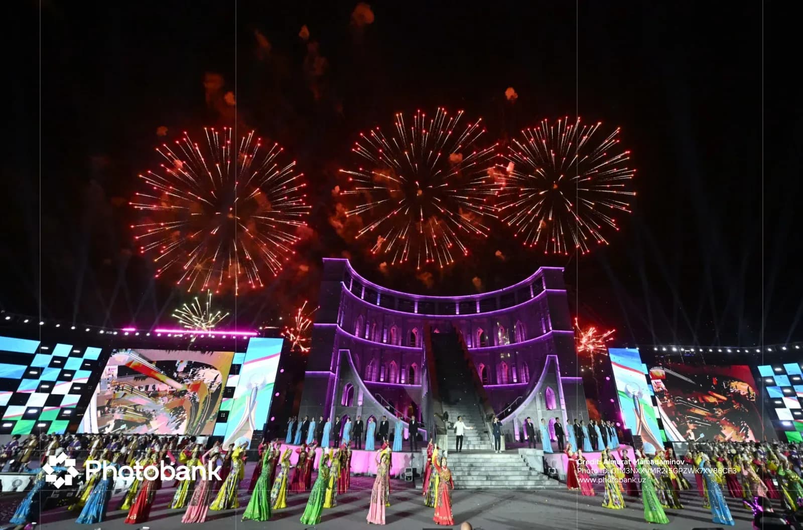 Festive celebration with fireworks over a lit stage and performers in traditional clothing