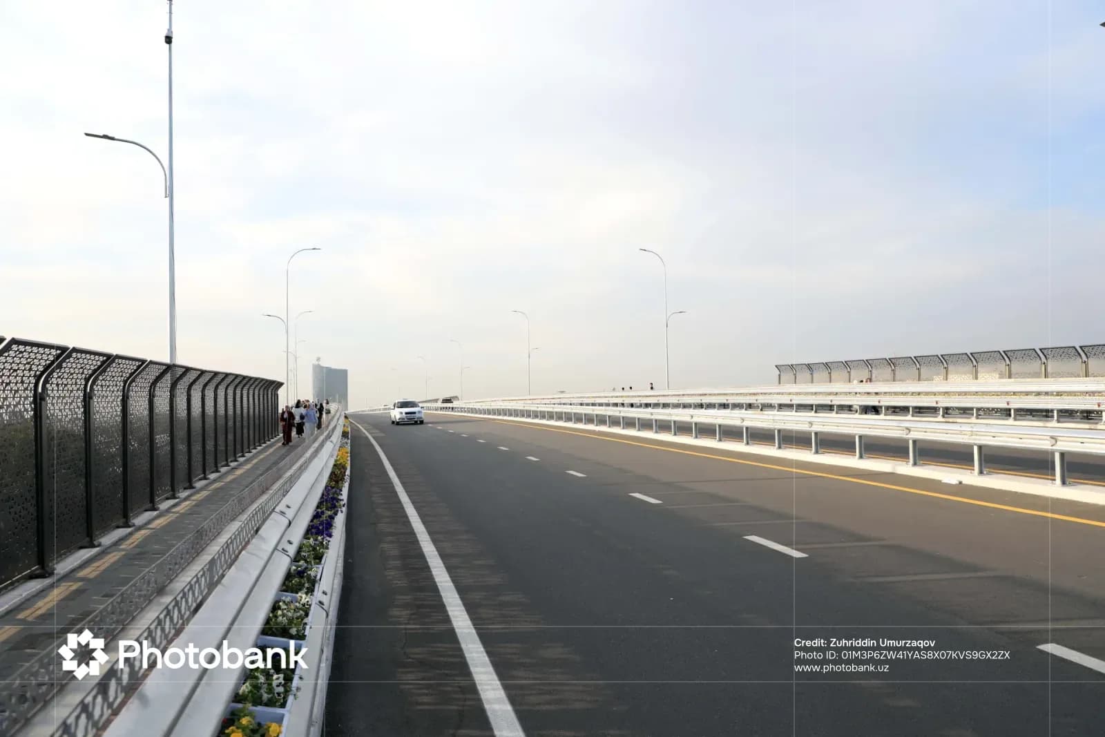 Modern highway bridge with pedestrian path and driving cars