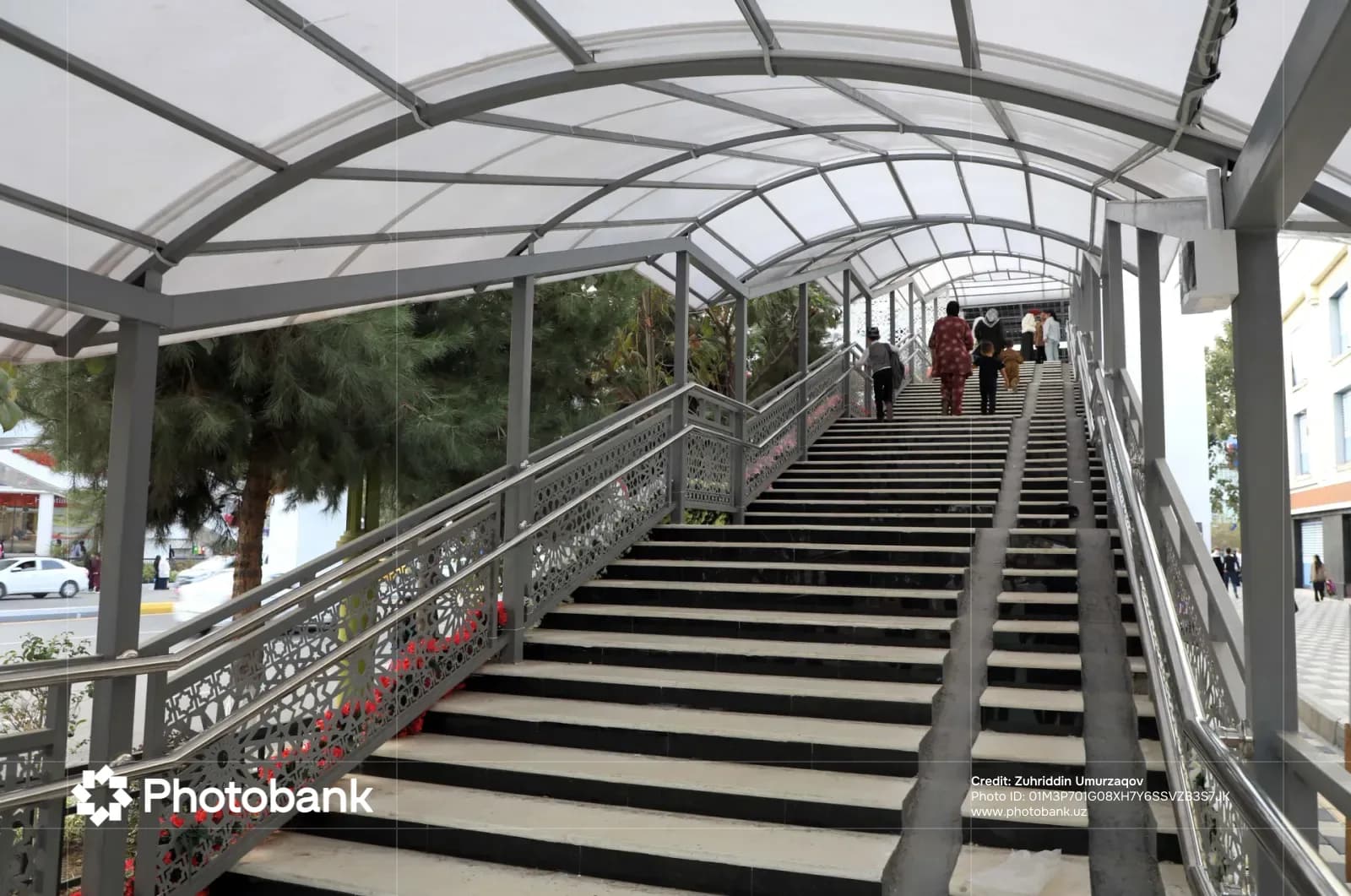 People walking up covered outdoor staircase with metal railings