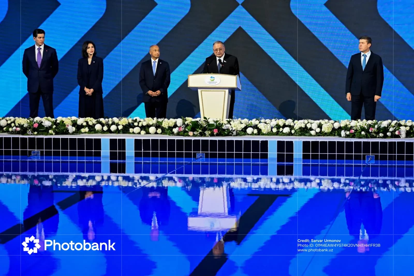 Odil Abdurahmonov speaking at an indoor event near a pool