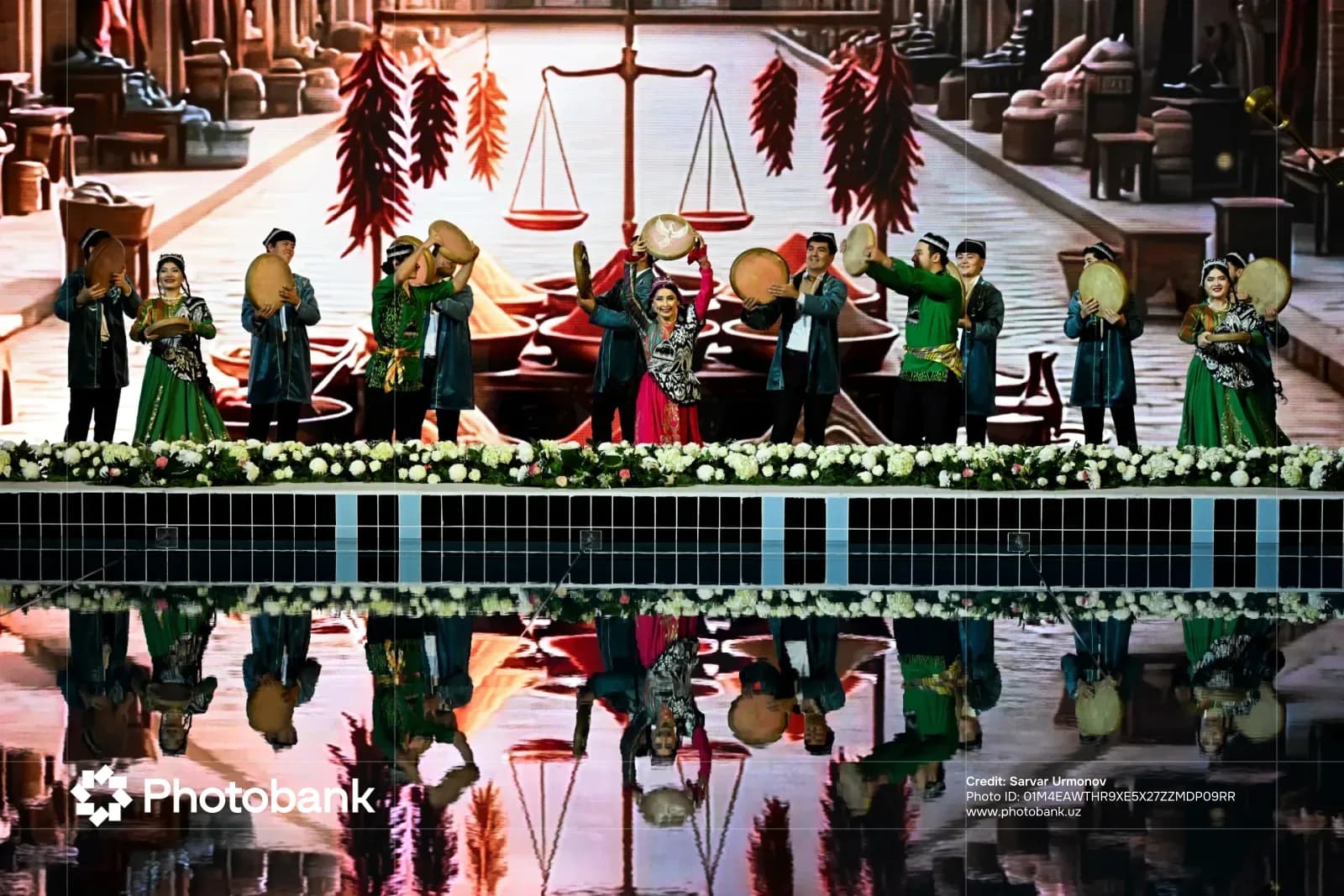 Performers in traditional clothing holding frame drums on a stage