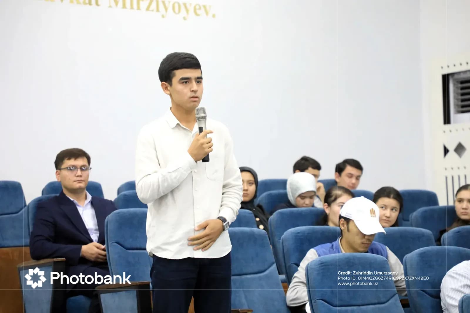 Молодой человек, говорящий в микрофон в аудитории