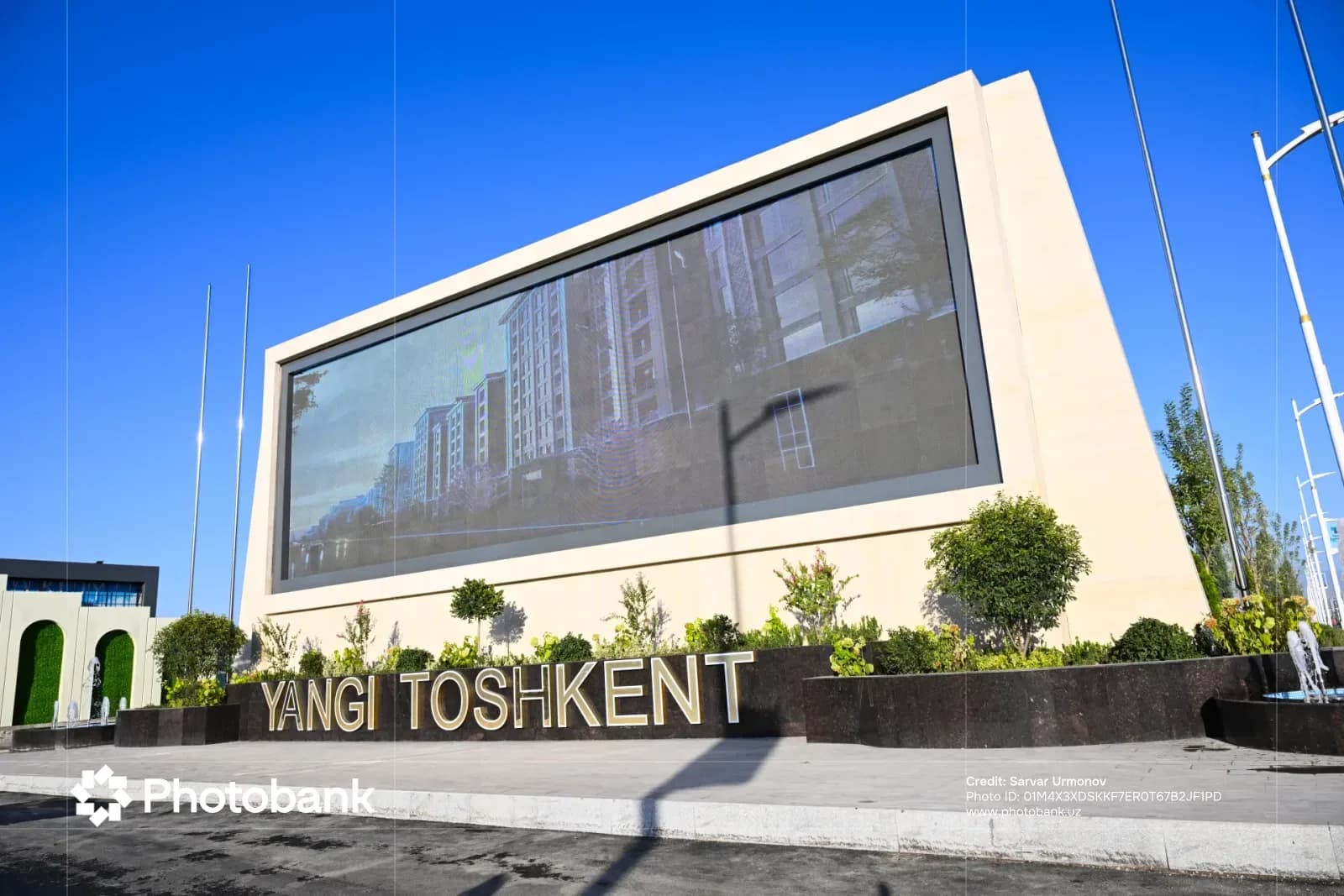 Large electronic display and sign reading Yangi Toshkent outdoors against a blue sky