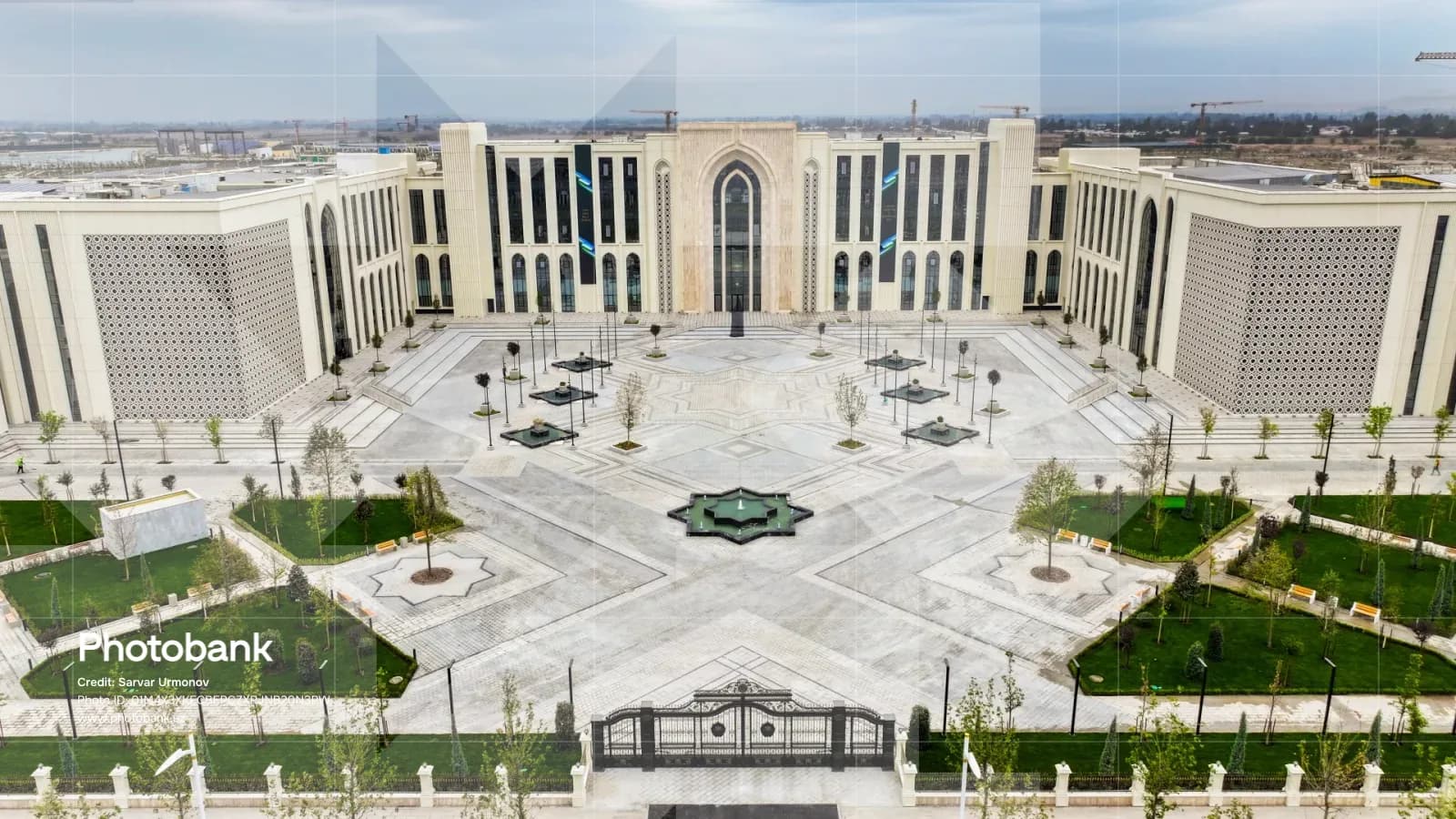Exterior view of a large modern building with a symmetrical courtyard and geometric paving