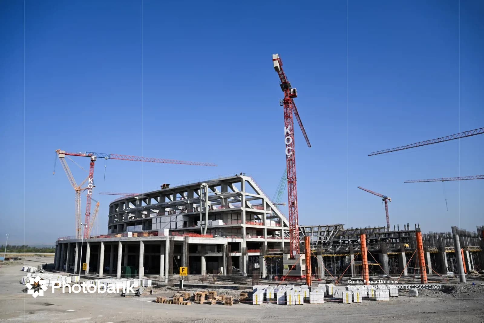 Construction site of a large concrete building with multiple cranes