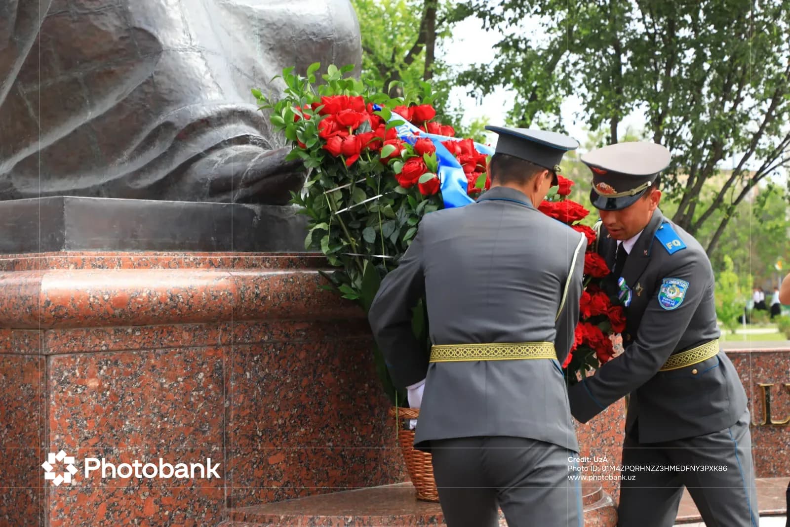 Люди в форме возлагают цветы к памятнику