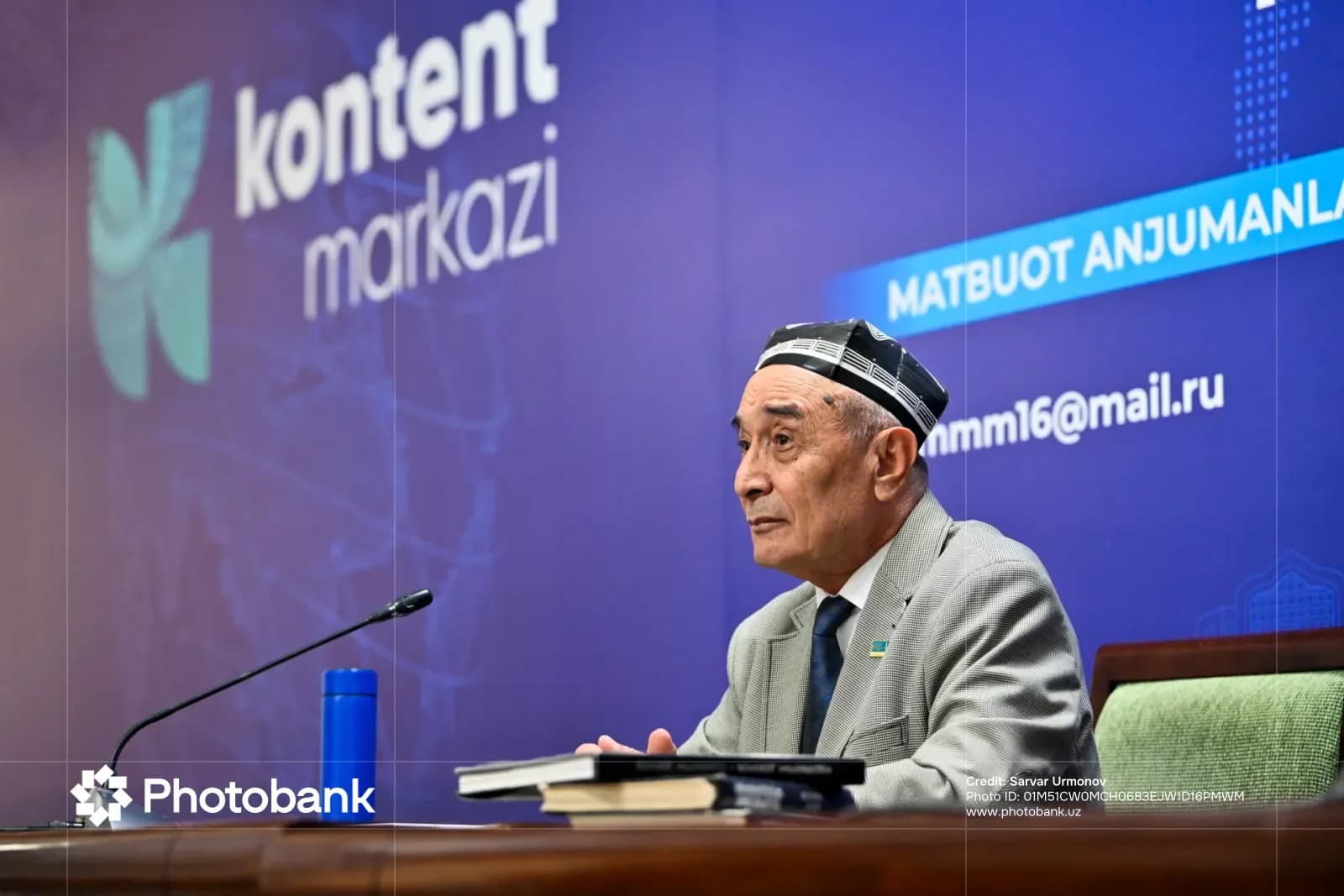 Человек, выступающий на конференции с микрофоном и книгами