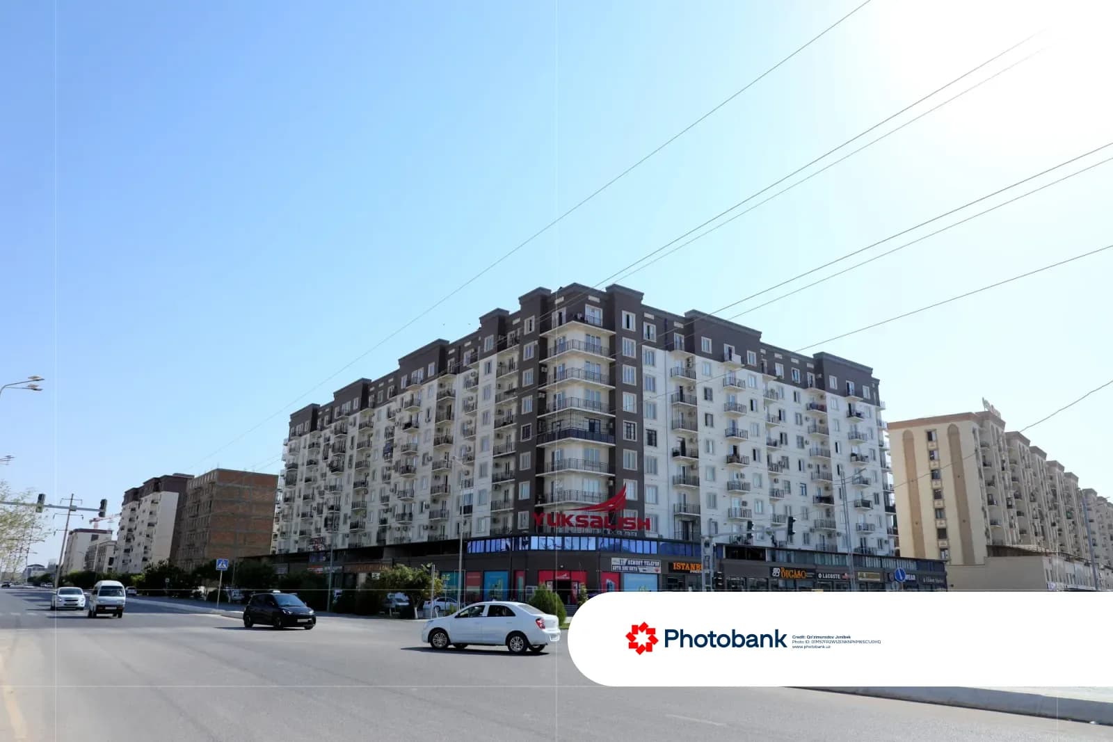 Многоэтажный многоквартирный дом вдоль городской улицы с движущимися транспортными средствами