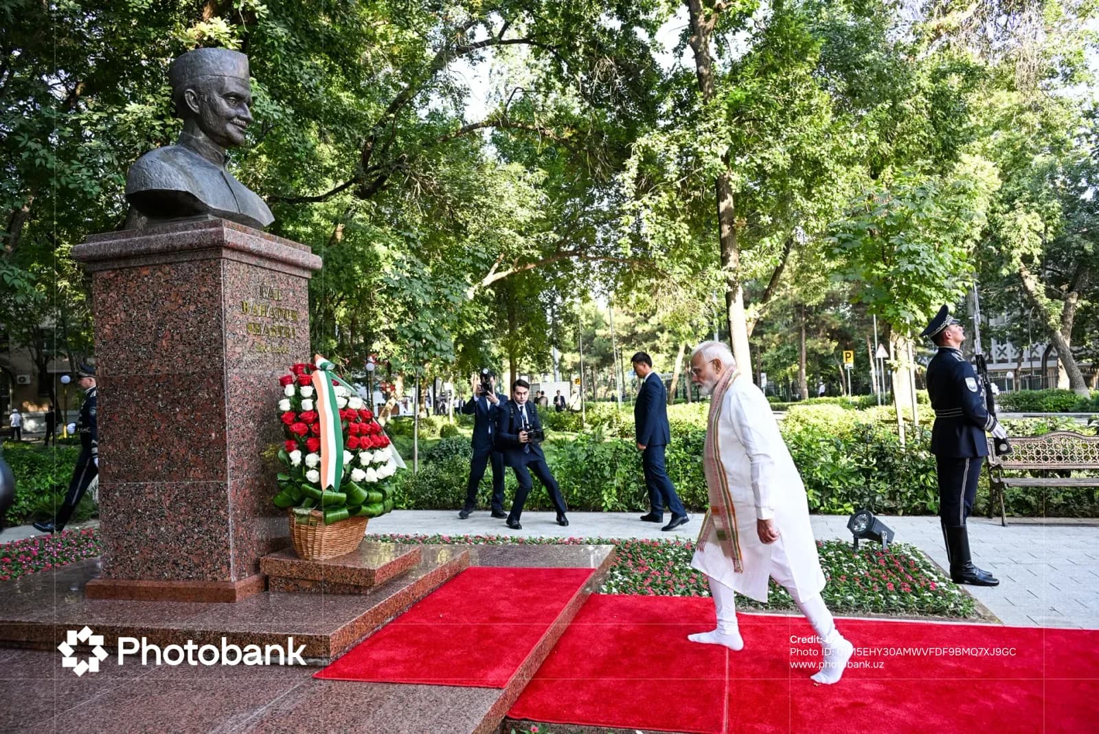 Человек, идущий по красной ковровой дорожке рядом с бюстом памятника