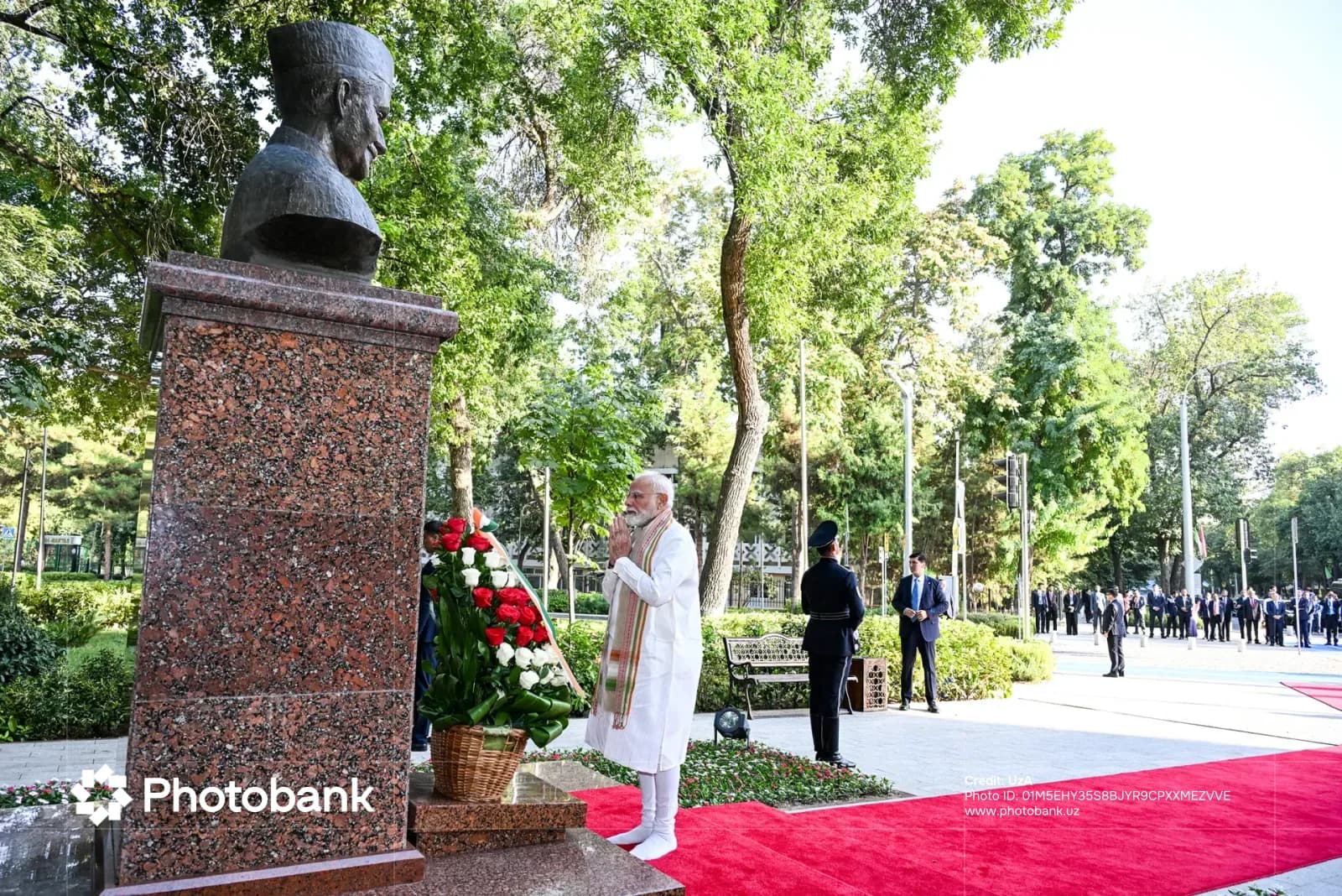 Человек, почтительно стоящий перед бюстом памятника на открытом воздухе
