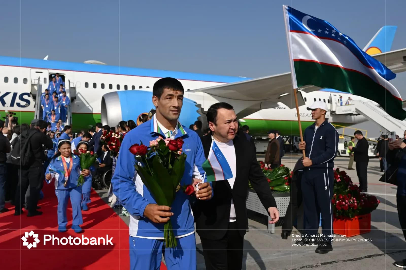 People holding flowers and flags near airplane