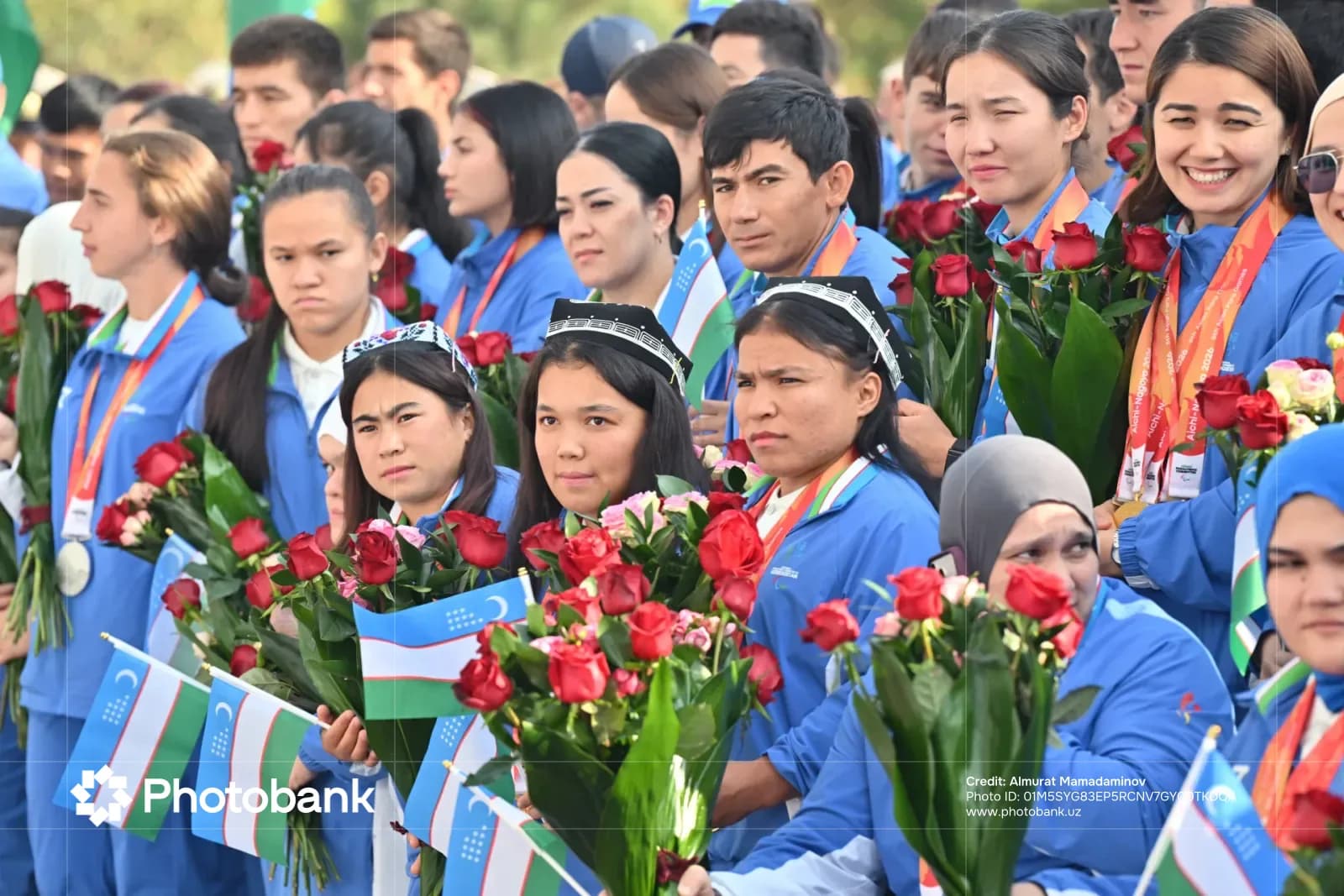 People holding bouquets of flowers and small flags in a gathering