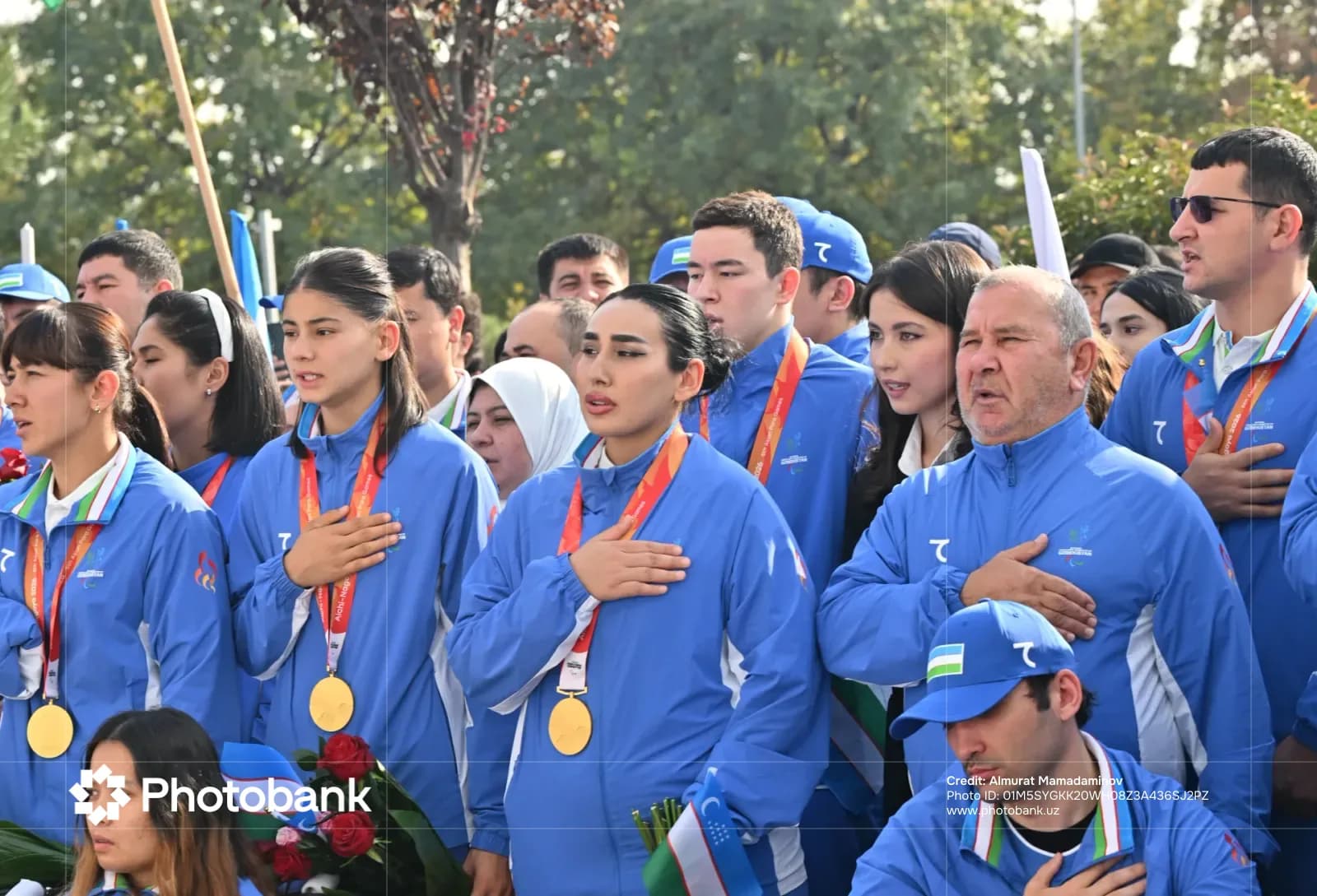 Group of people in sportswear placing hands on chests outdoors