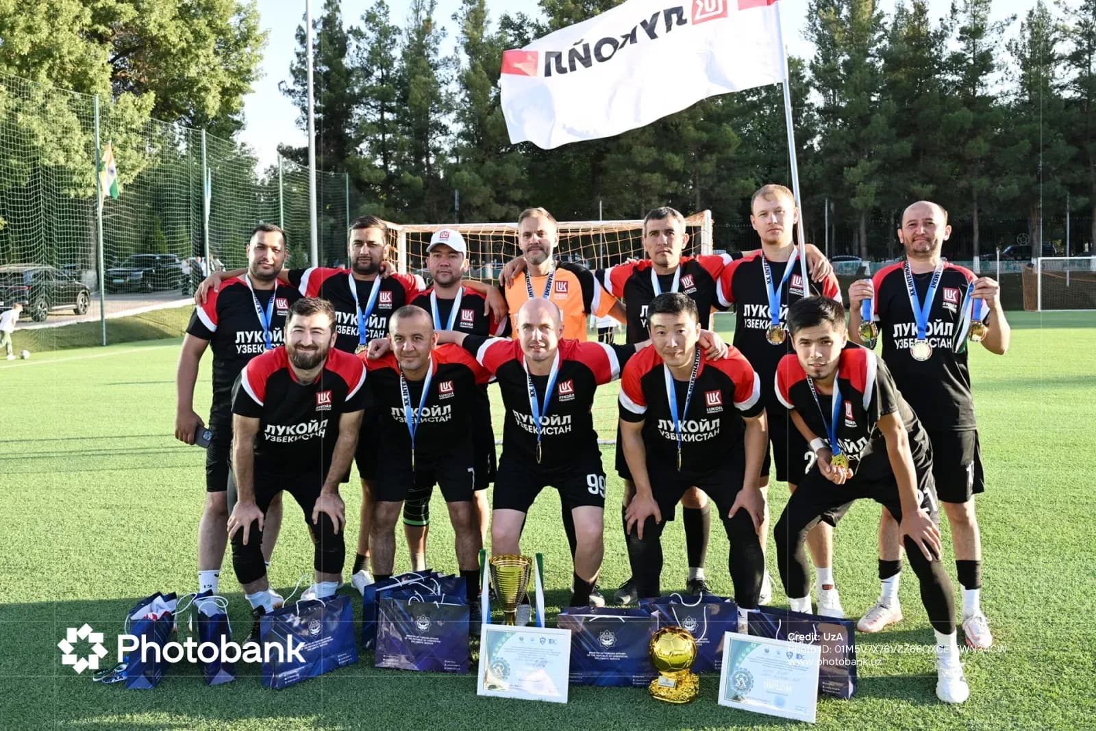 Спортивная команда позирует с медалями и трофеями на поле