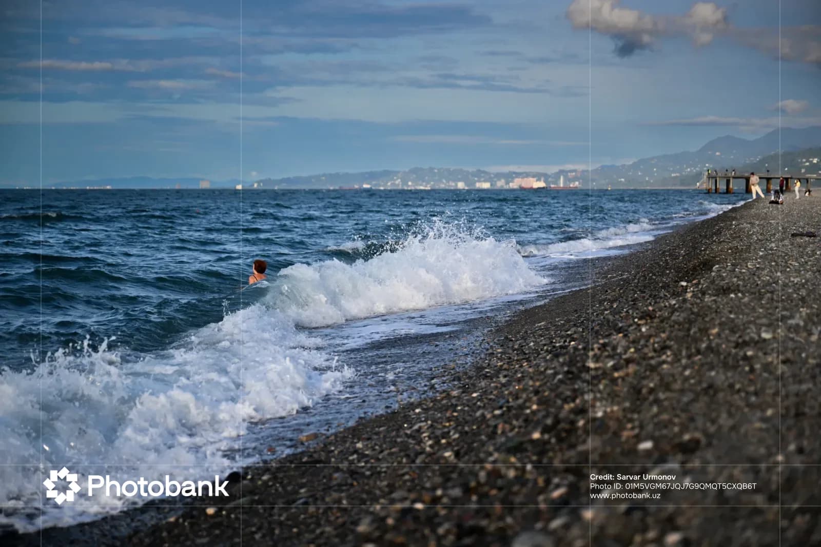 Person swimming in sea near pebble beach