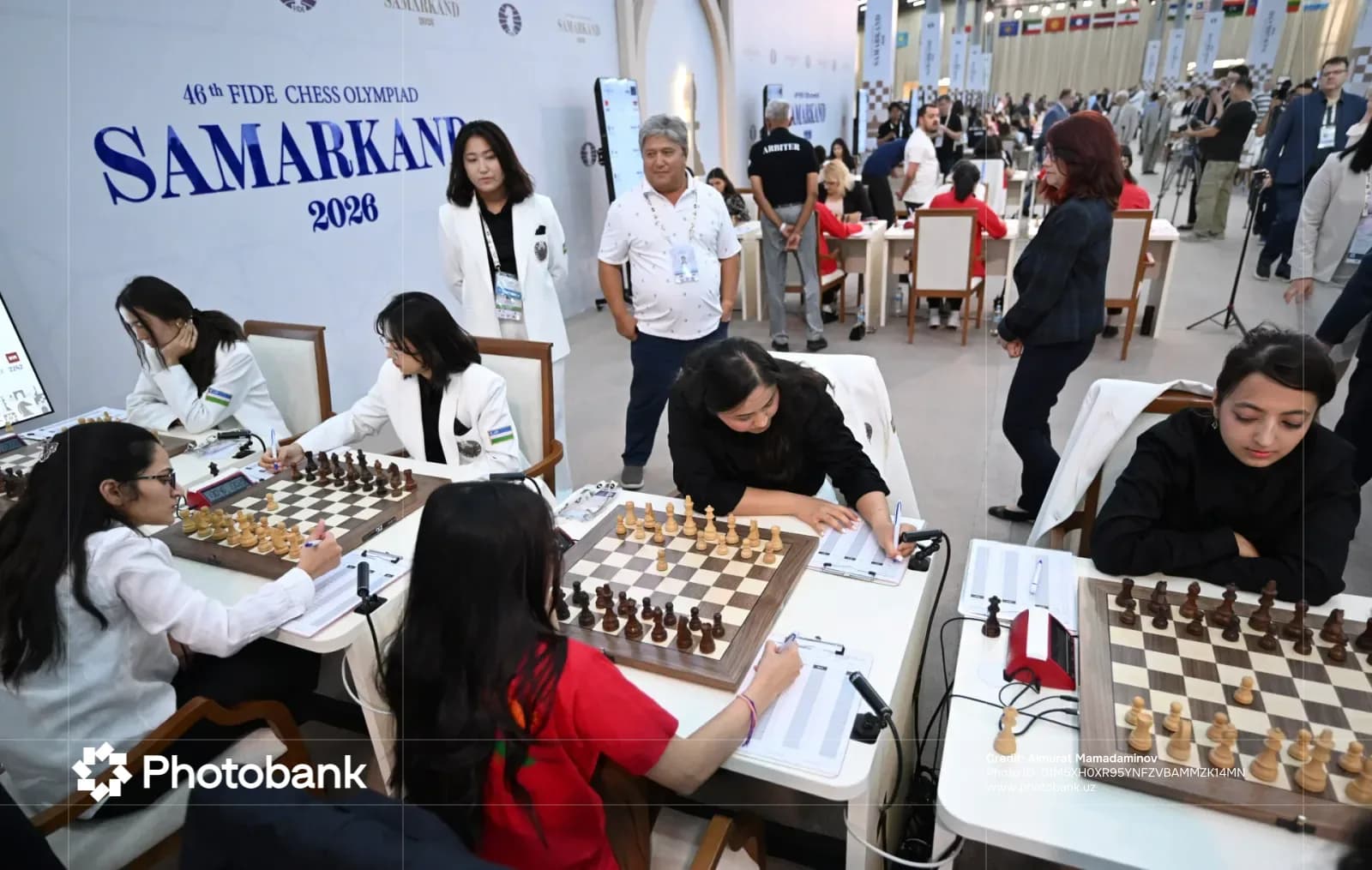 Players compete at chess boards during a competition in a large hall