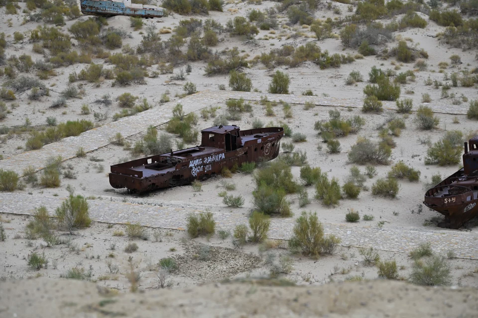 Rusted shipwrecks resting on a sandy desert landscape