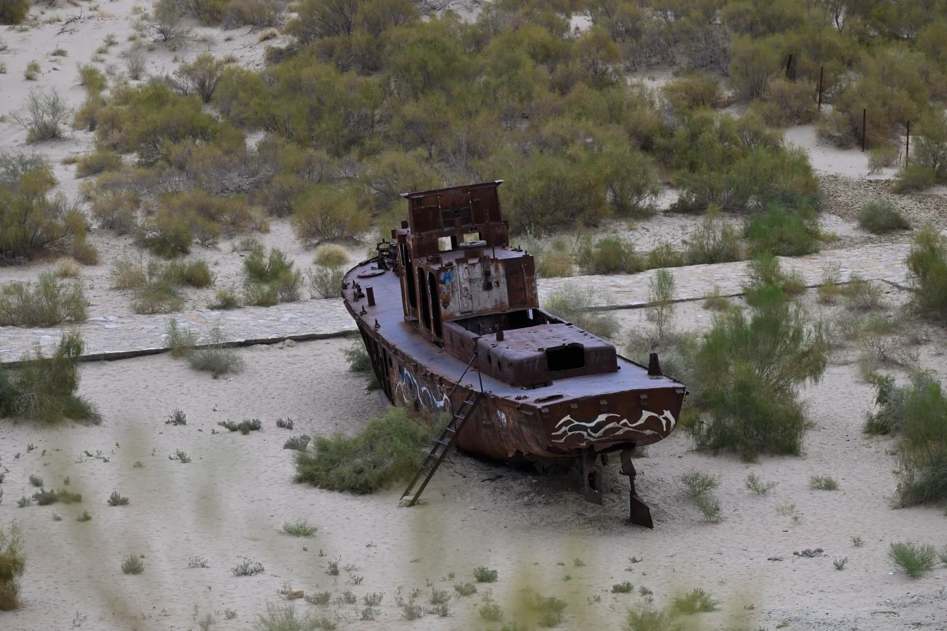 A rusted shipwreck stranded in a dry sandy landscape