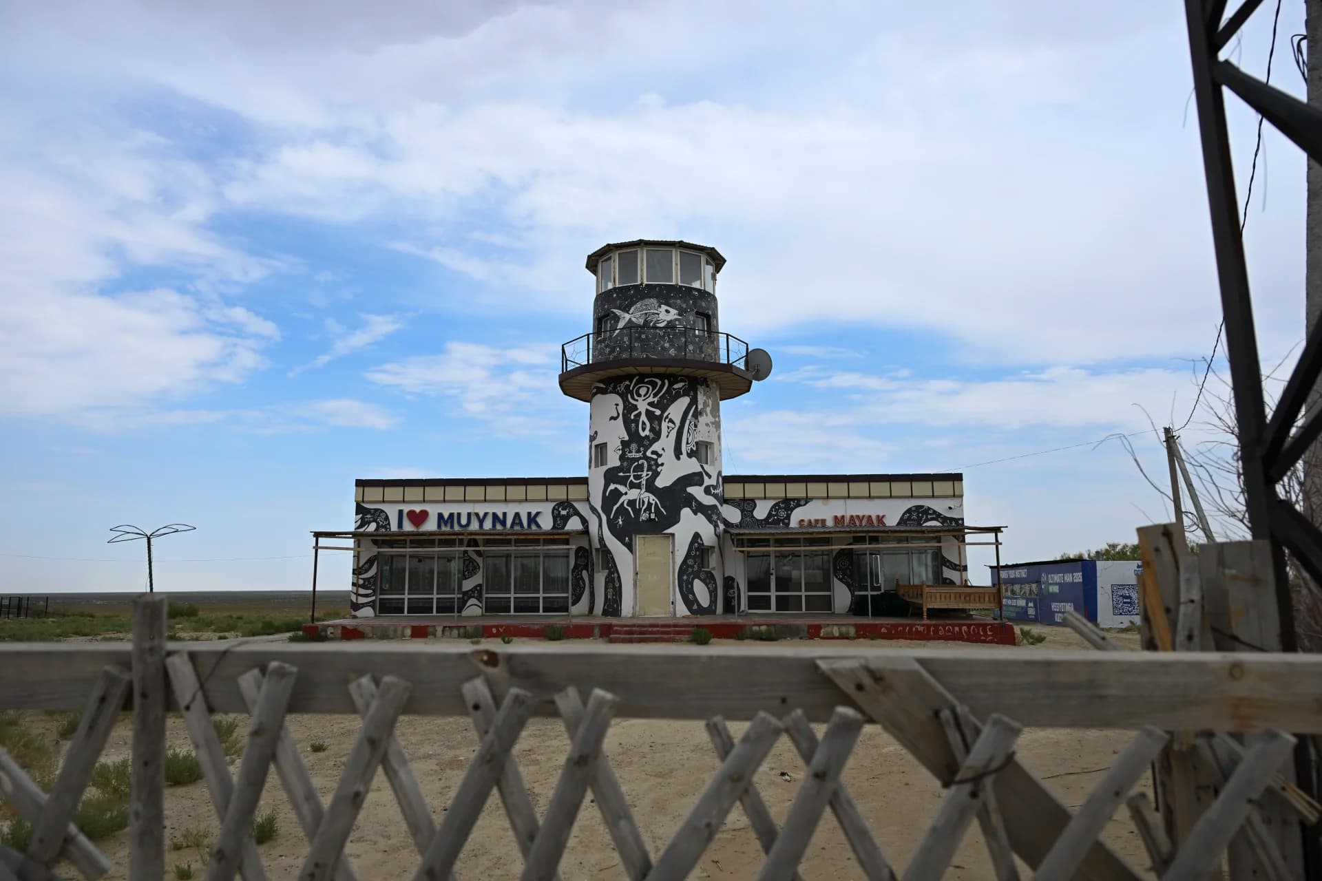 Lighthouse-shaped building decorated with murals in a flat landscape