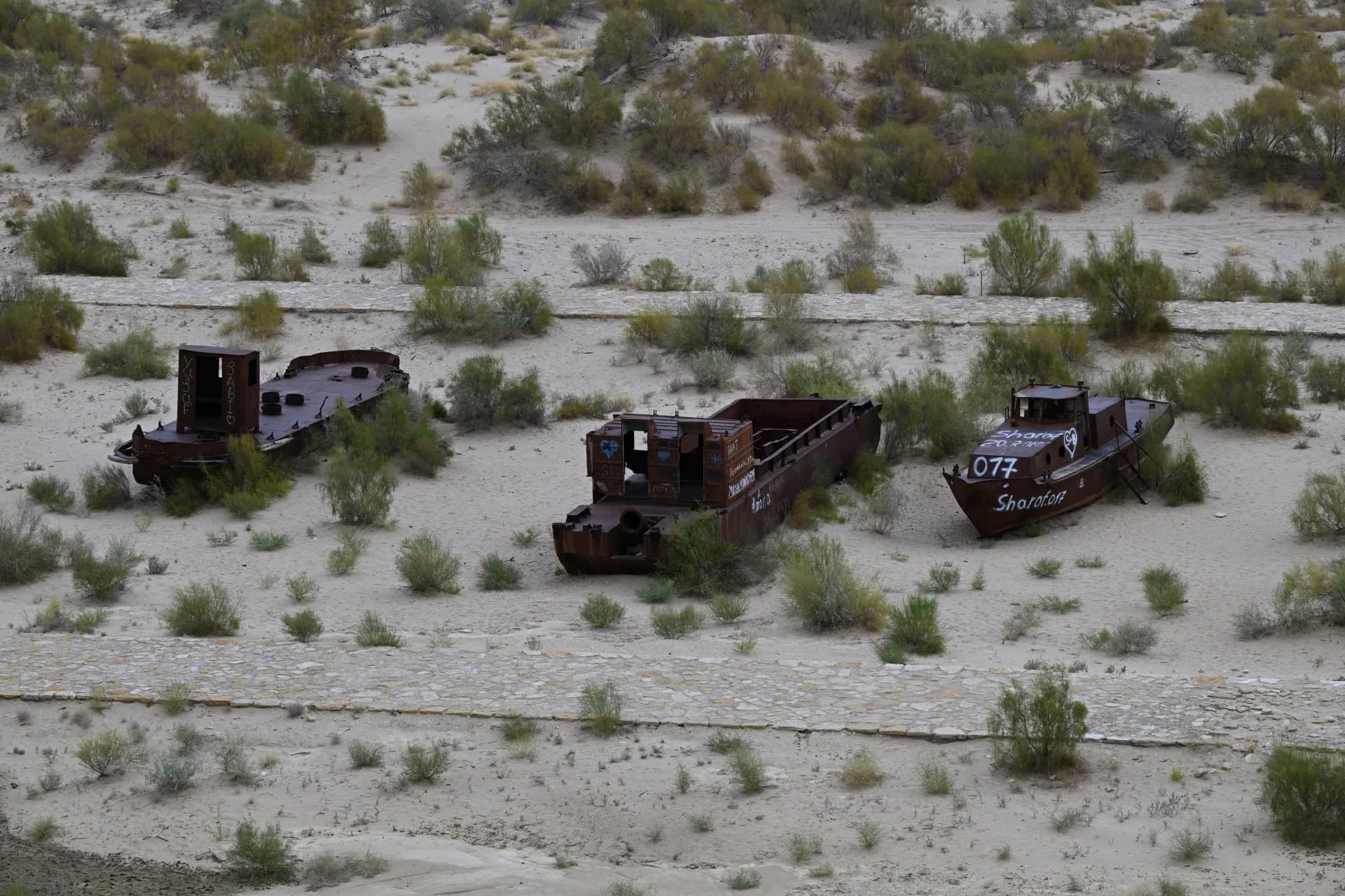 Rusted metal boat wrecks resting in a dry sandy landscape