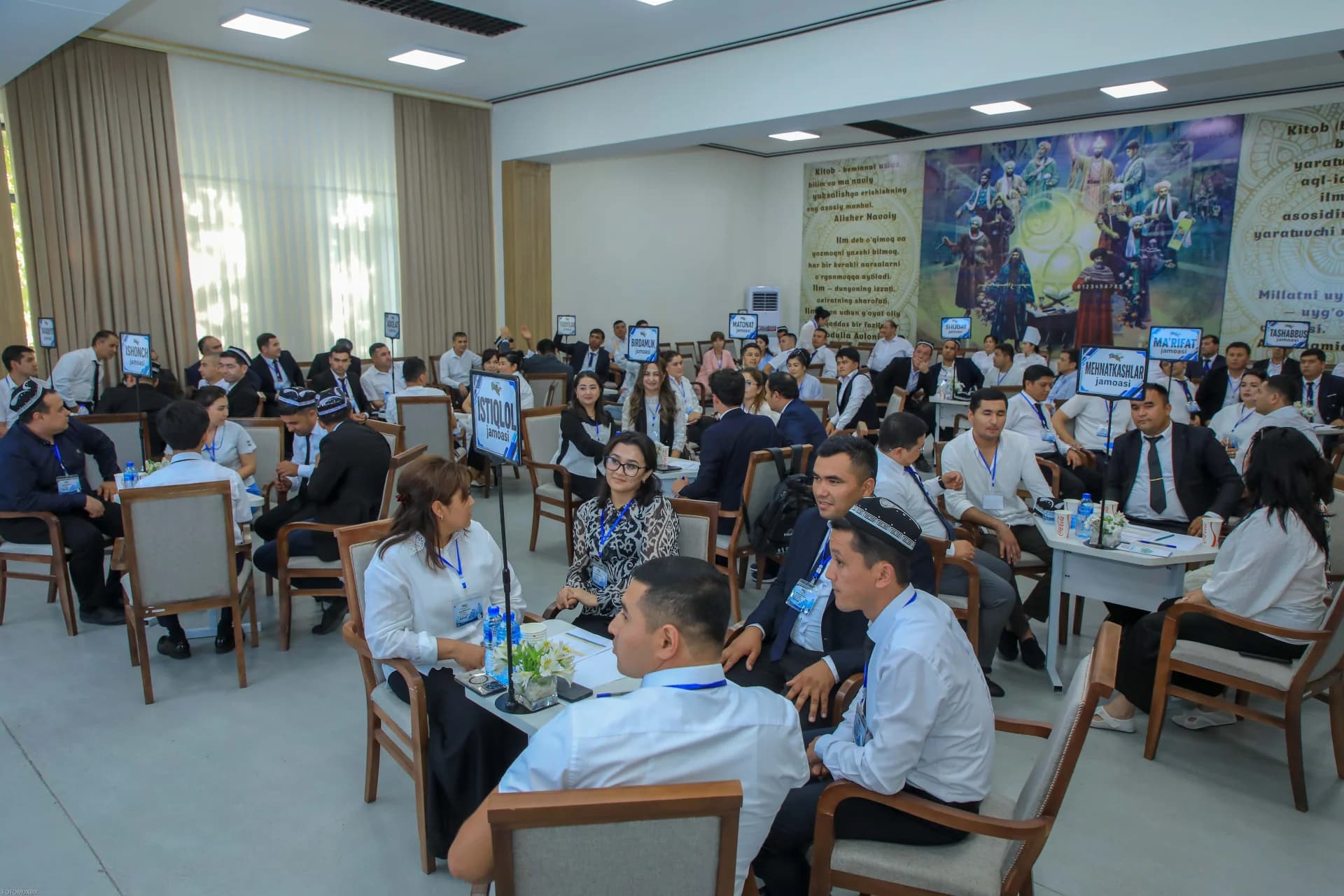People seated at tables during a gathering in a hall