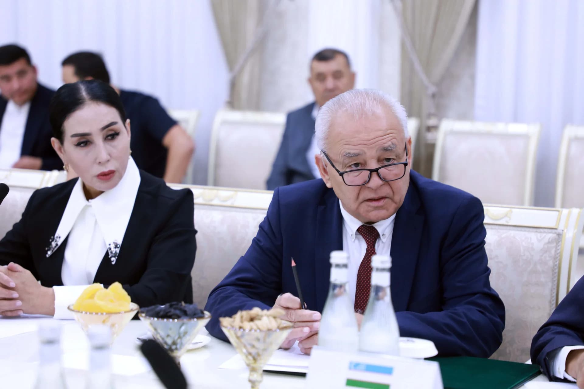 Люди, присутствующие на официальном собрании, сидящие за конференц-столом