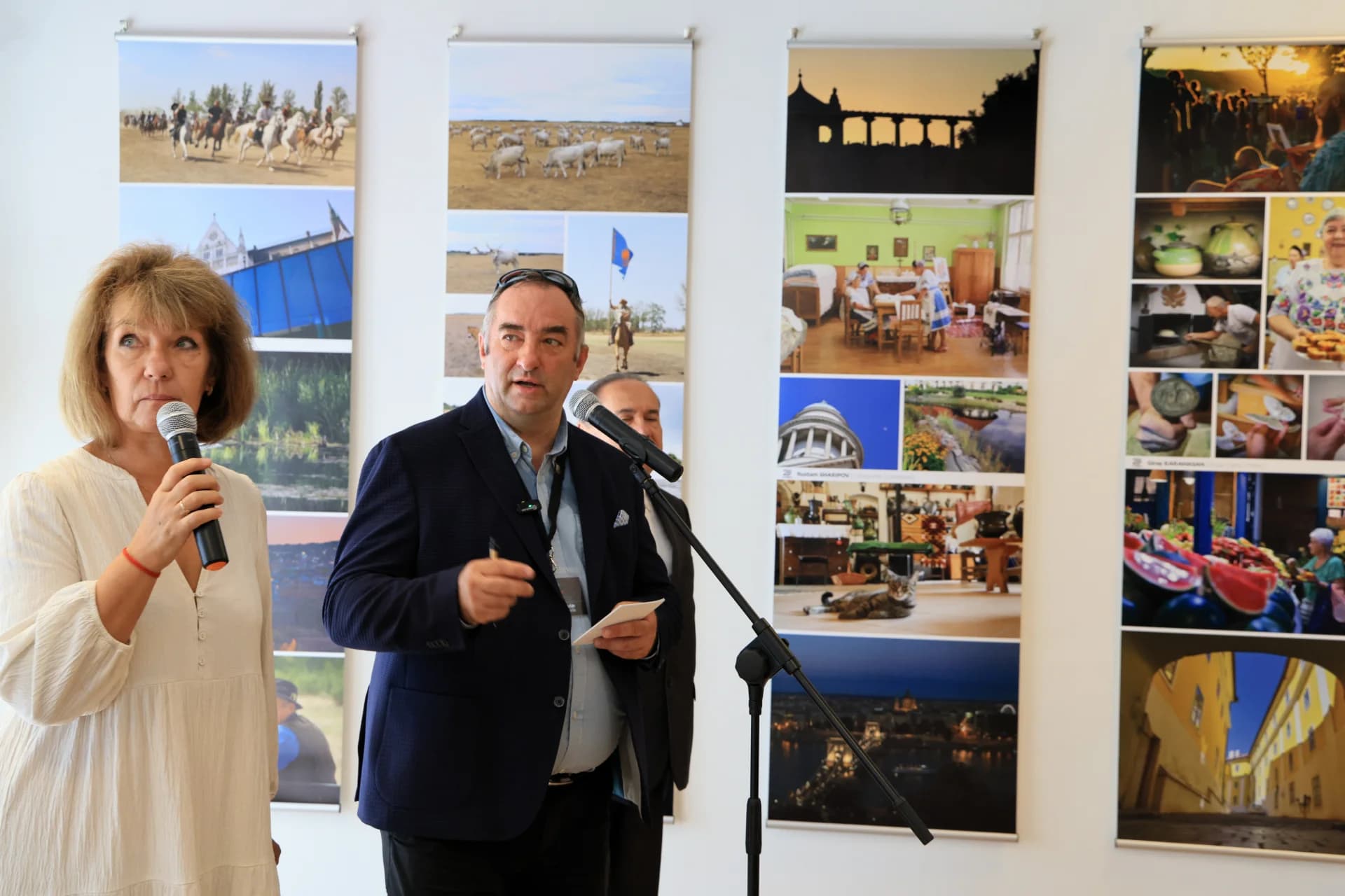 People speaking at an event in front of photo displays