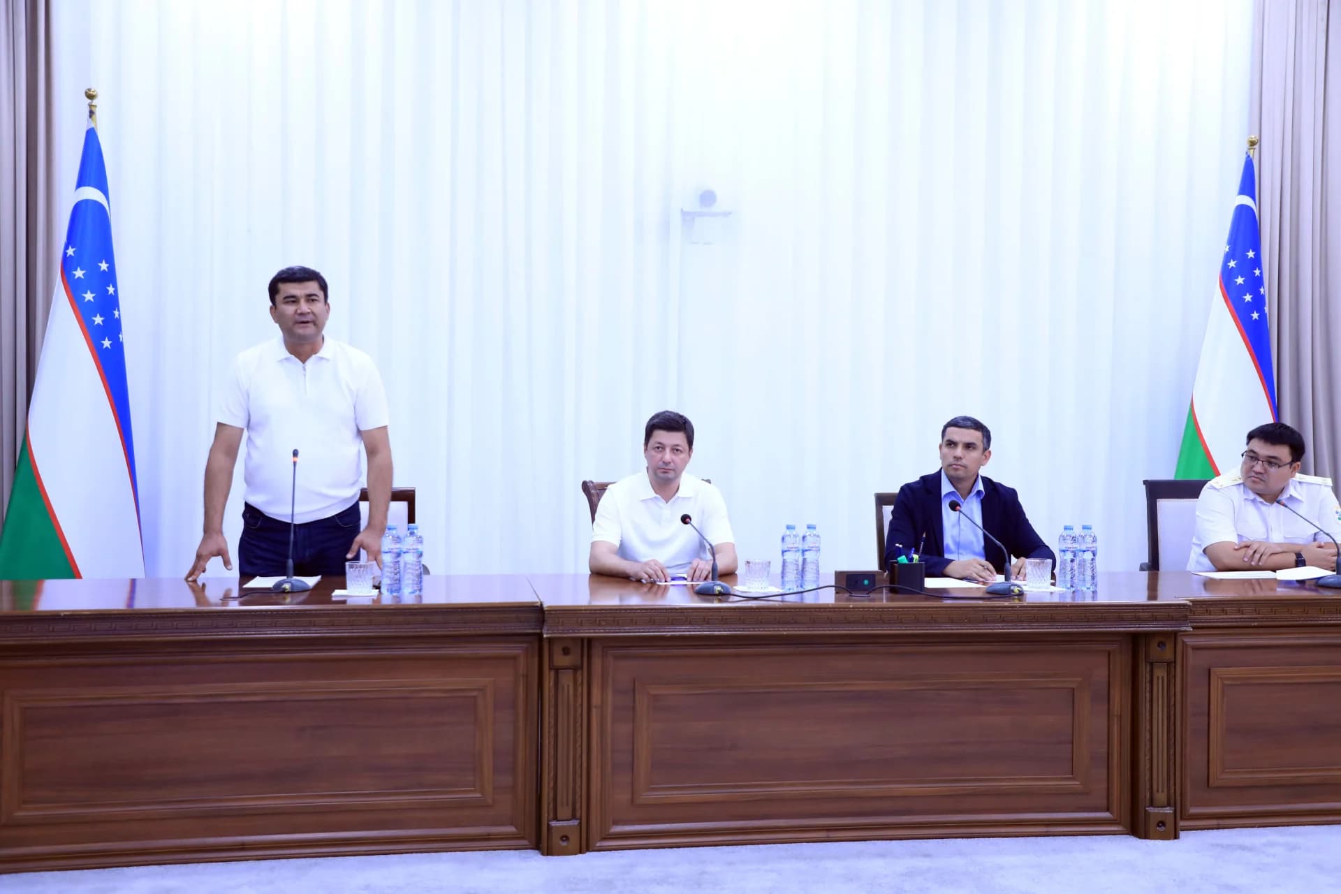 People gathered at a conference table with flags
