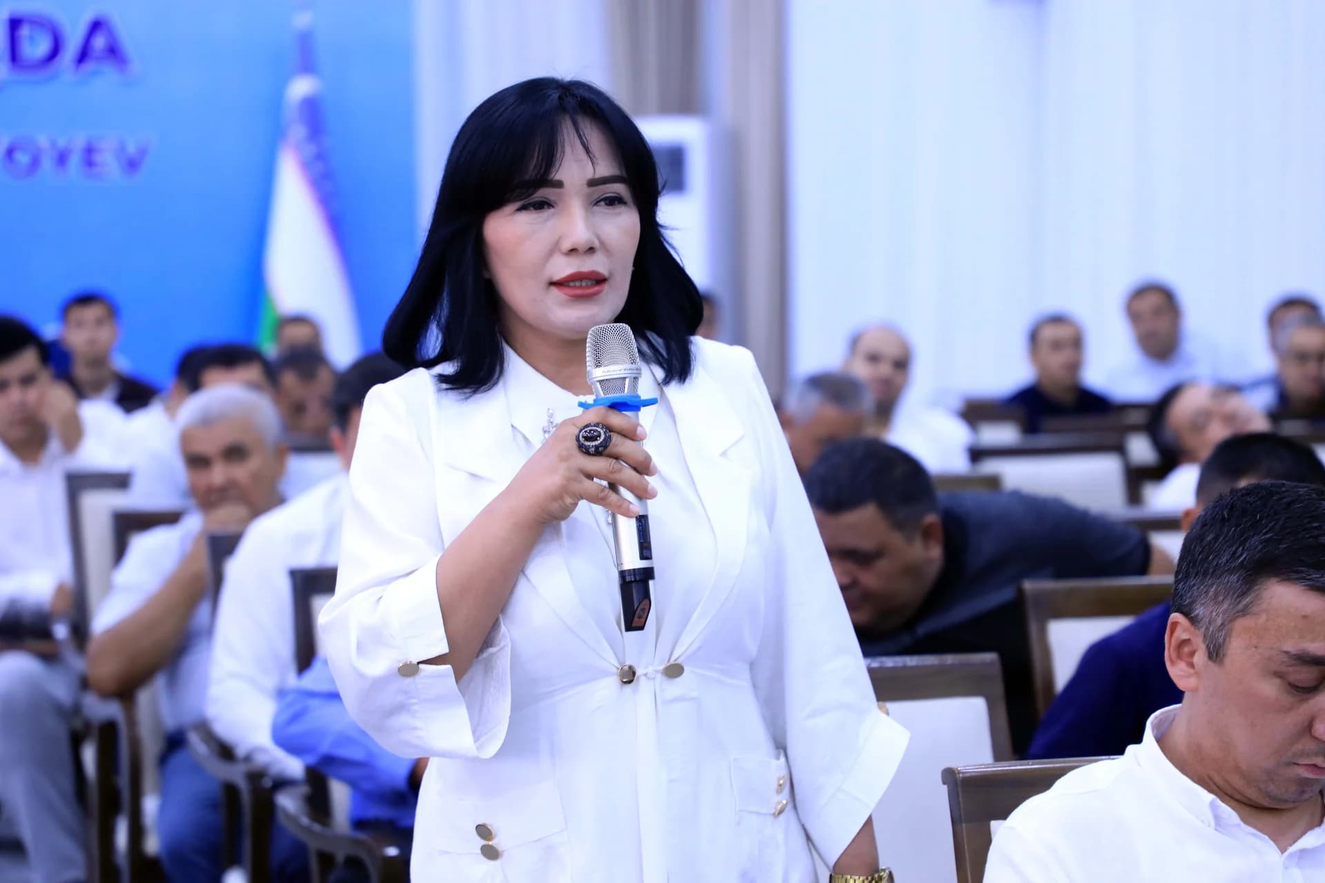 Woman speaking into a microphone during an indoor gathering