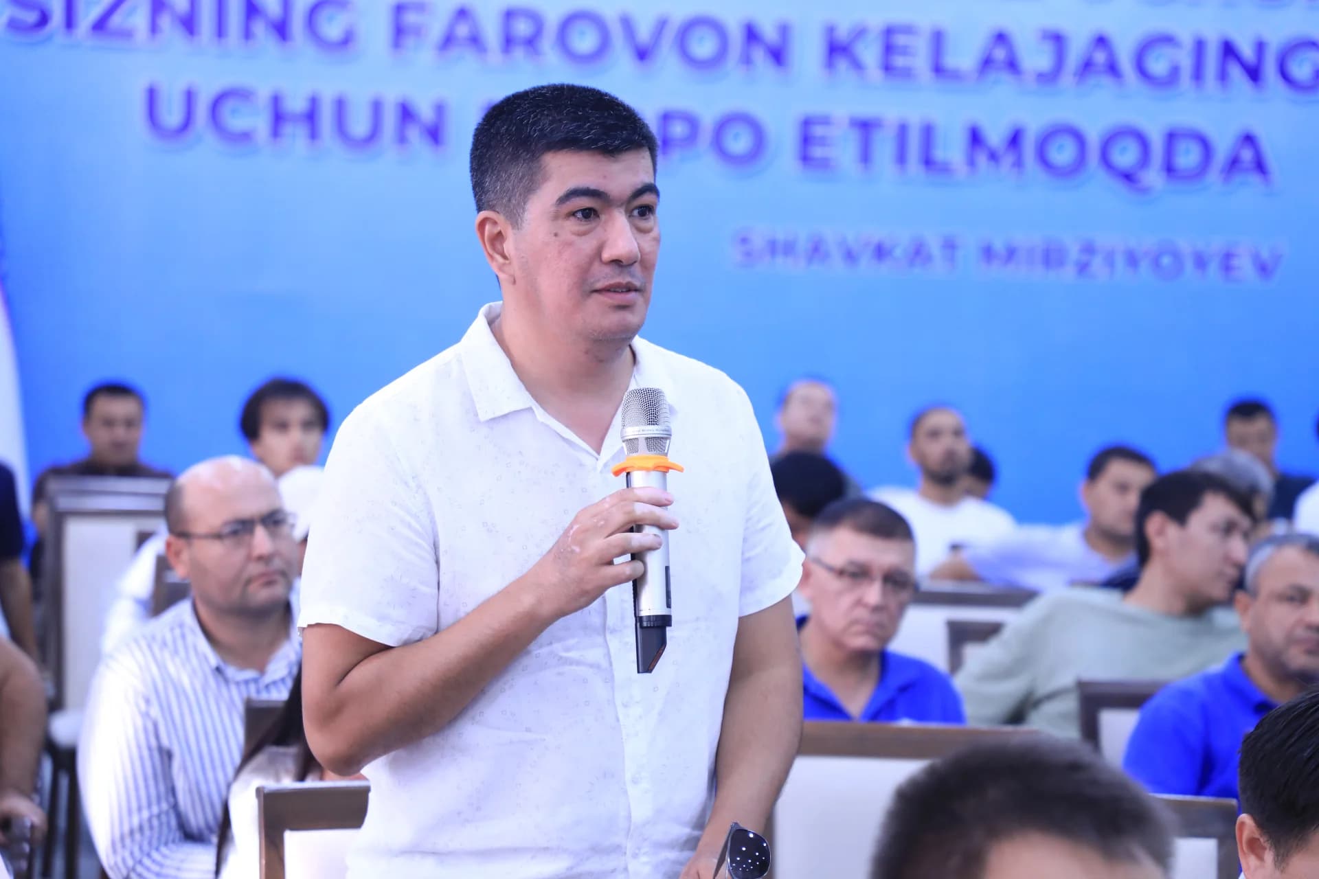 Man speaking into microphone at indoor conference event